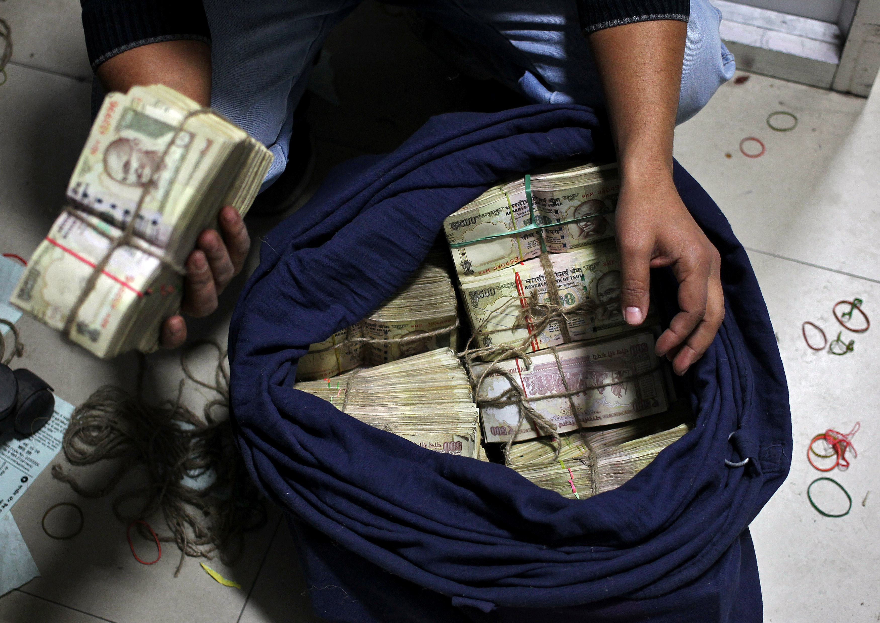 A bank employee takes out a bundle of old 500 Indian rupee banknotes from a sack to count them inside a bank in Jammu