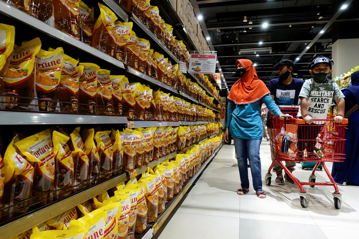People shop for cooking oil made from oil palms at a supermarket in Jakarta