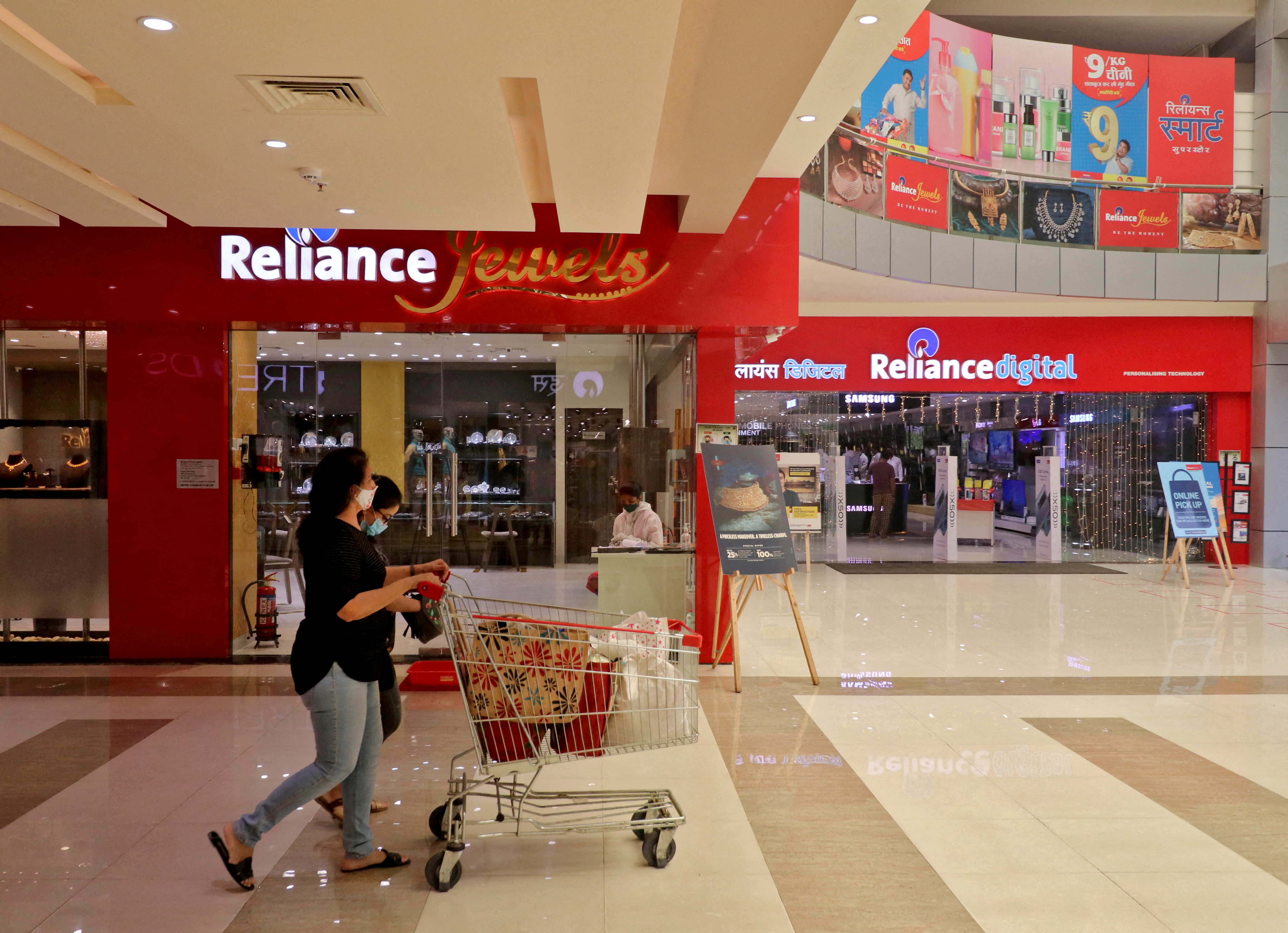 Customers walk past stores of Reliance Industries Ltd, in Mumbai