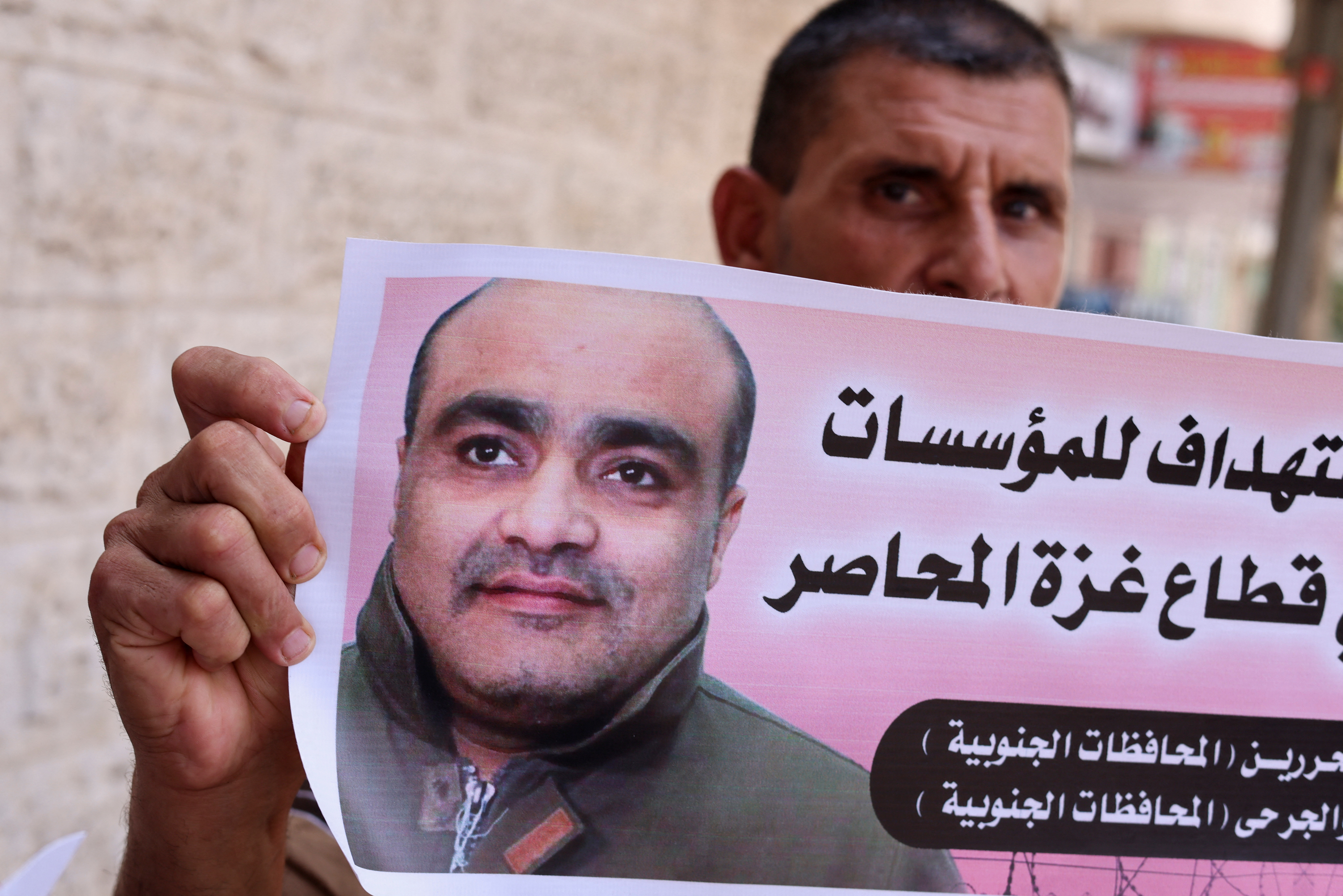 A man holds a picture of Mohammad El Halabi, during a solidarity gathering following an Israeli court decision to sentence him for 12 years, outside the office of the International Committee of the Red Cross in Gaza City