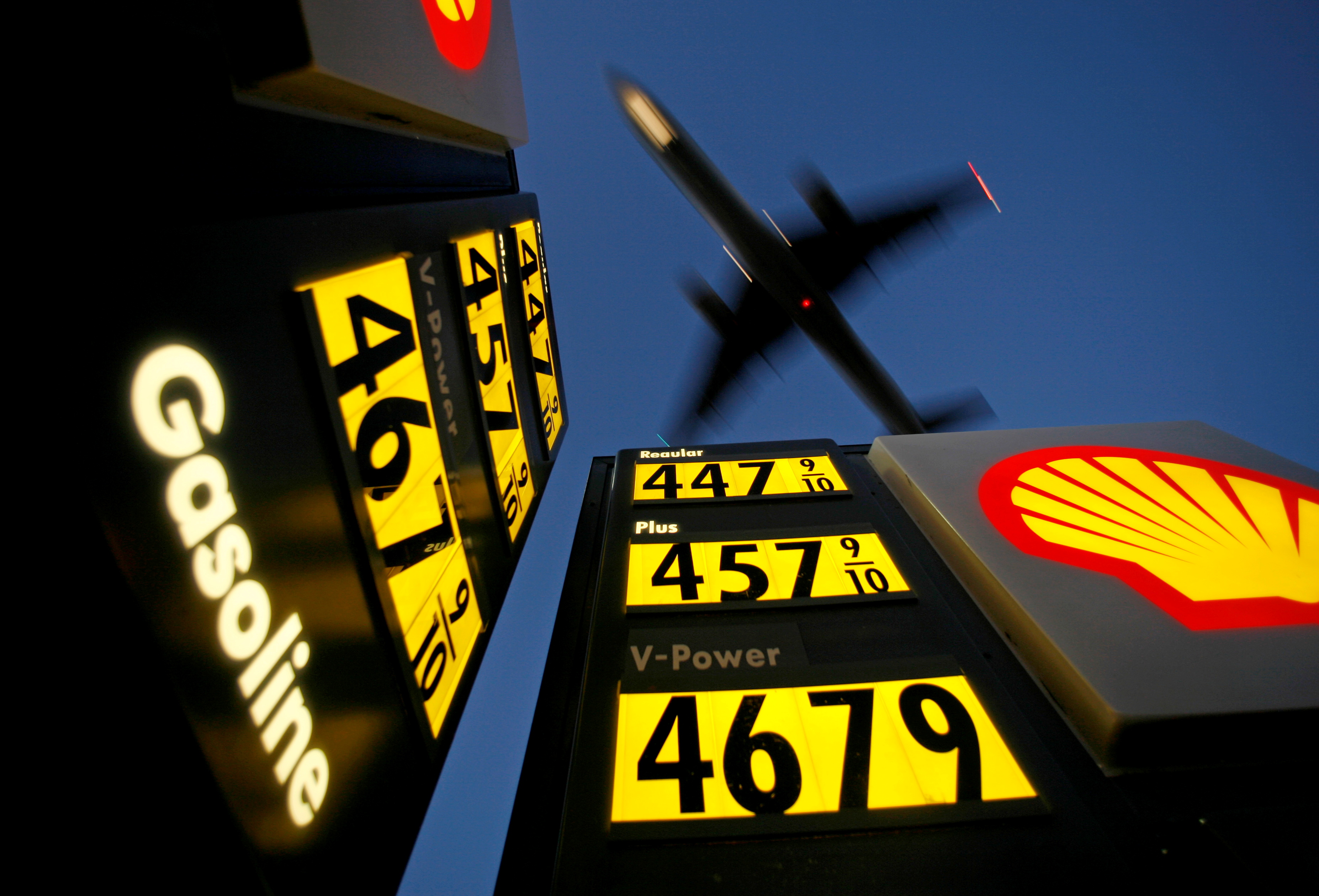 Gasoline prices are advertised at a gas station near Lindbergh Field as a plane approaches to land in San Diego
