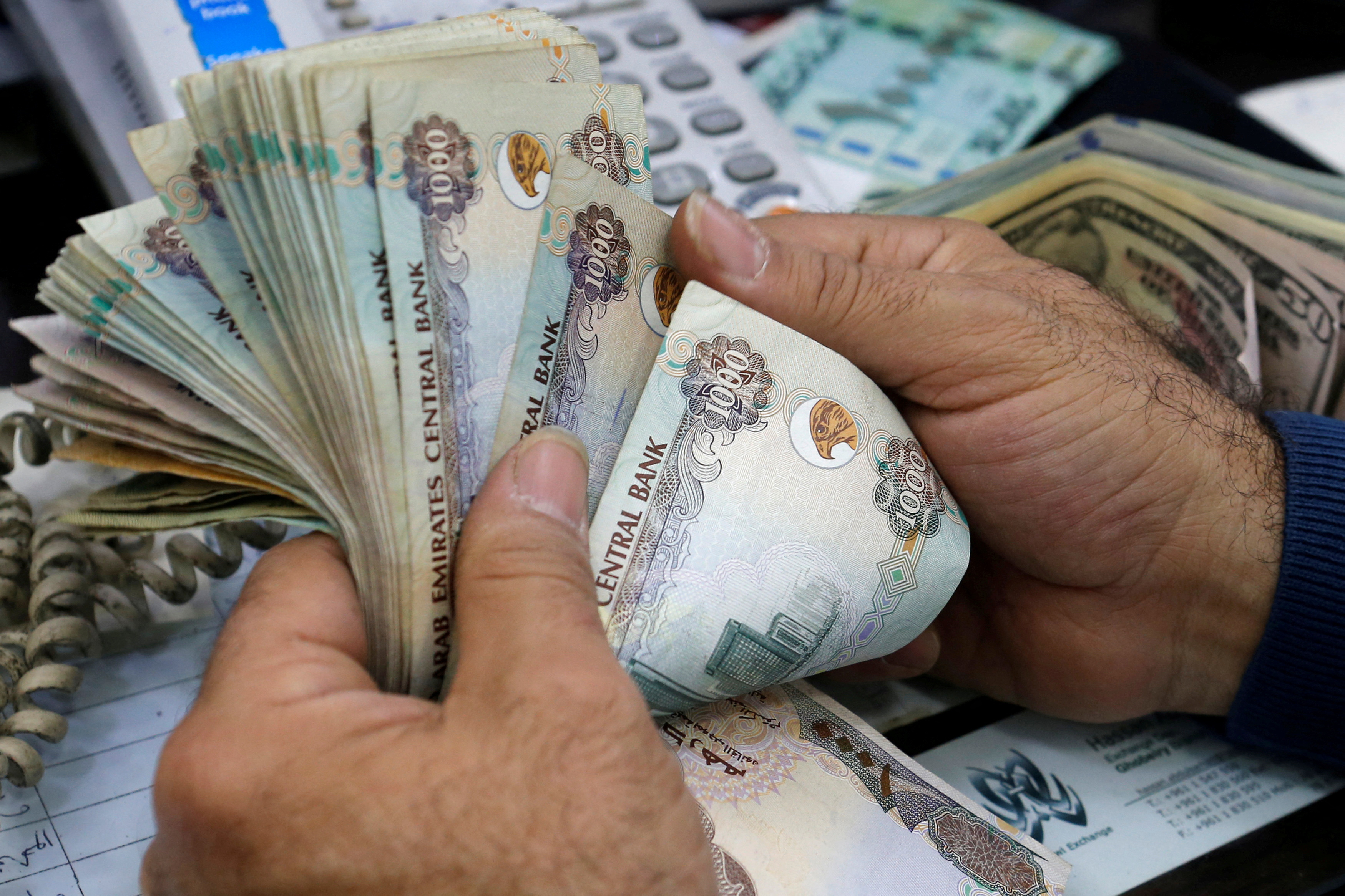 A money exchange vendor counts United Arab Emirates dirhams at his shop in Beirut