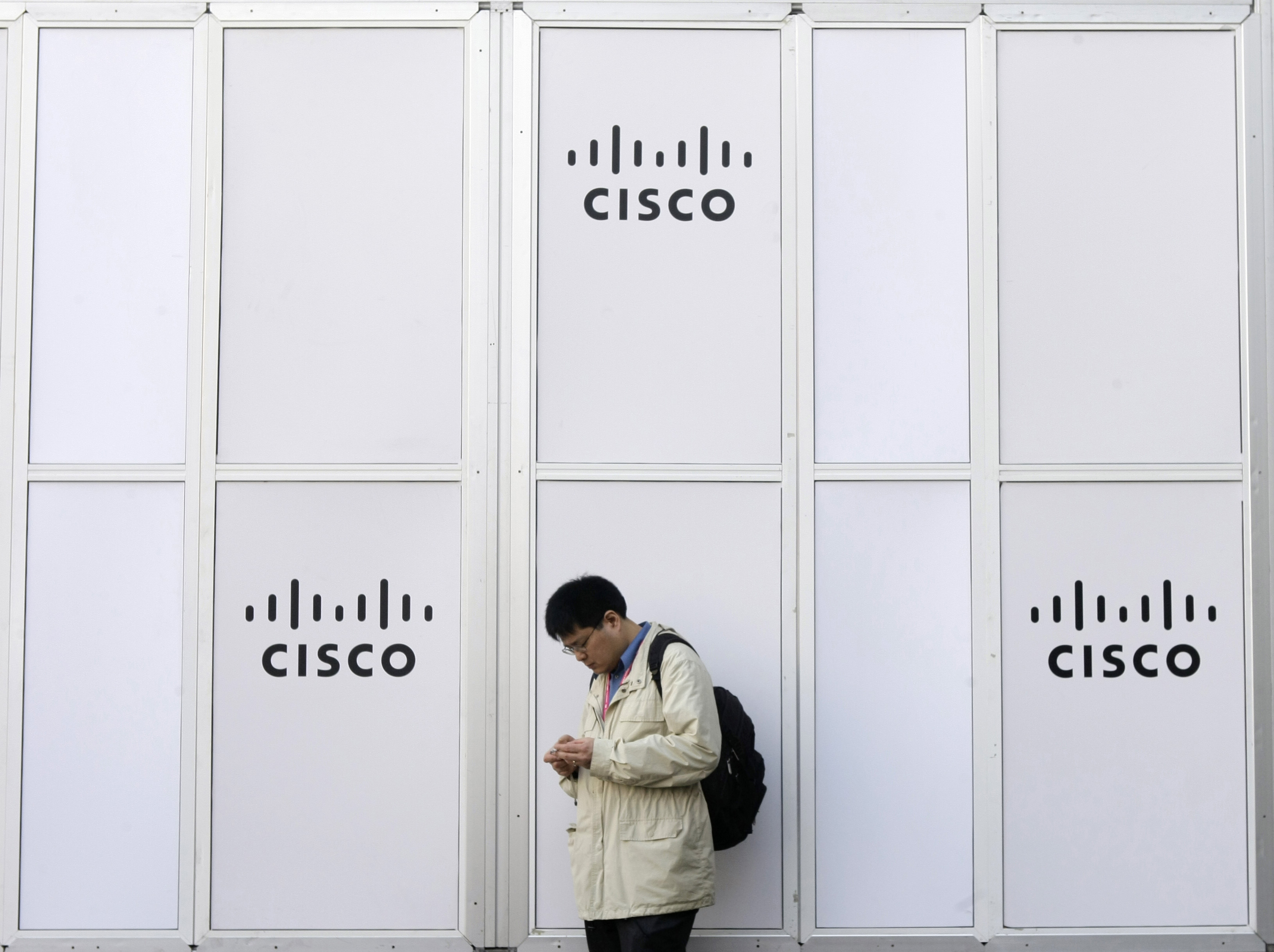 A man looks at his mobile next to a Cisco banner at the Mobile World Congress in Barcelona