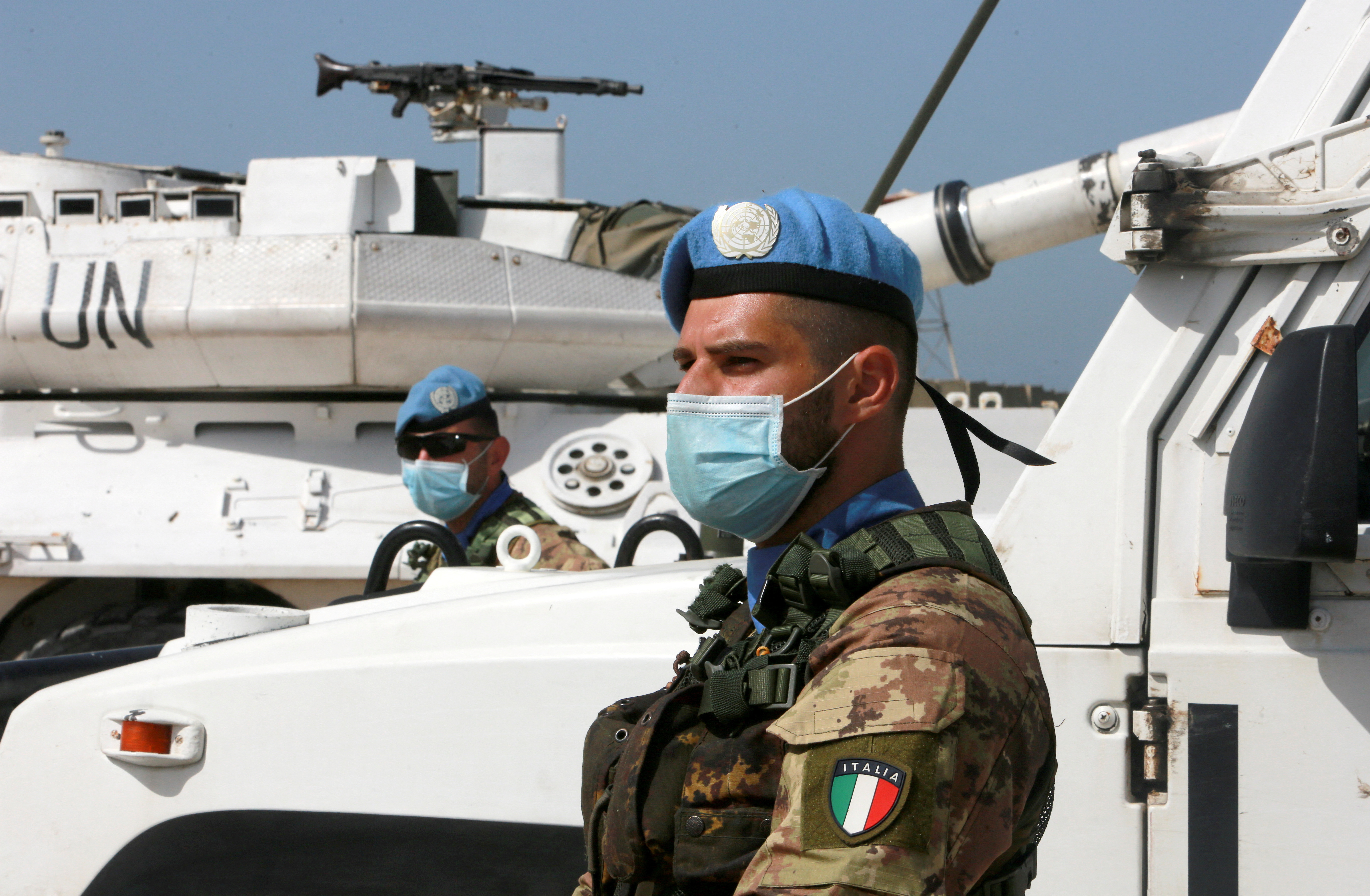 A UN peacekeeper (UNIFIL) wears a face mask as he stands past a UN vehicles in Naqoura