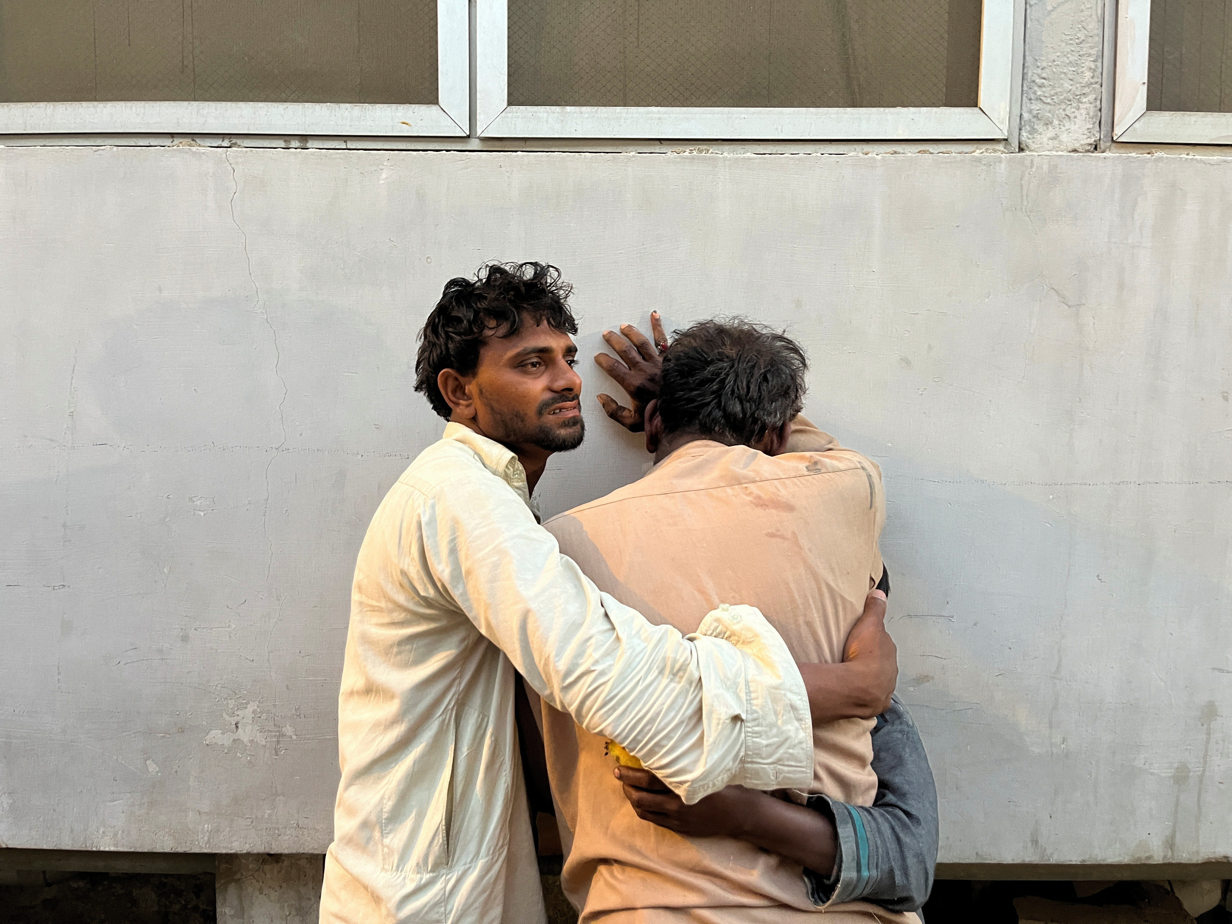 Men mourn the death of relative, who was killed along with others in a stampede at a distribution site for food aid in Karachi