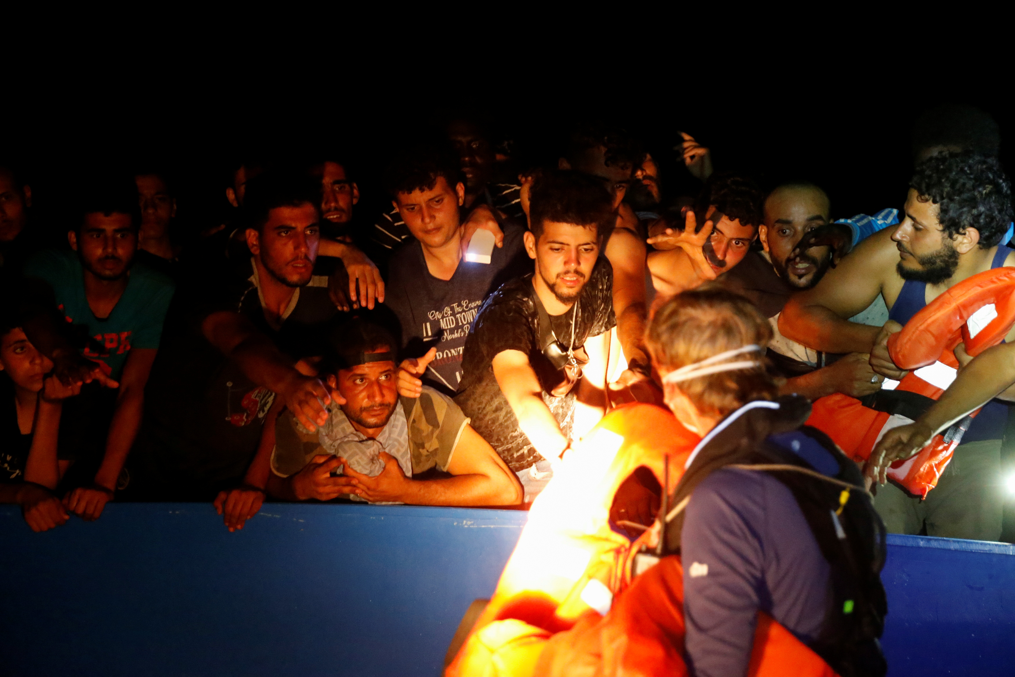 A RHIB (rigid hulled inflatable boat) crew member from the German NGO migrant rescue ship Sea-Watch 3 distributes life jackets to migrants.
REUTERS/Darrin Zammit Lupi