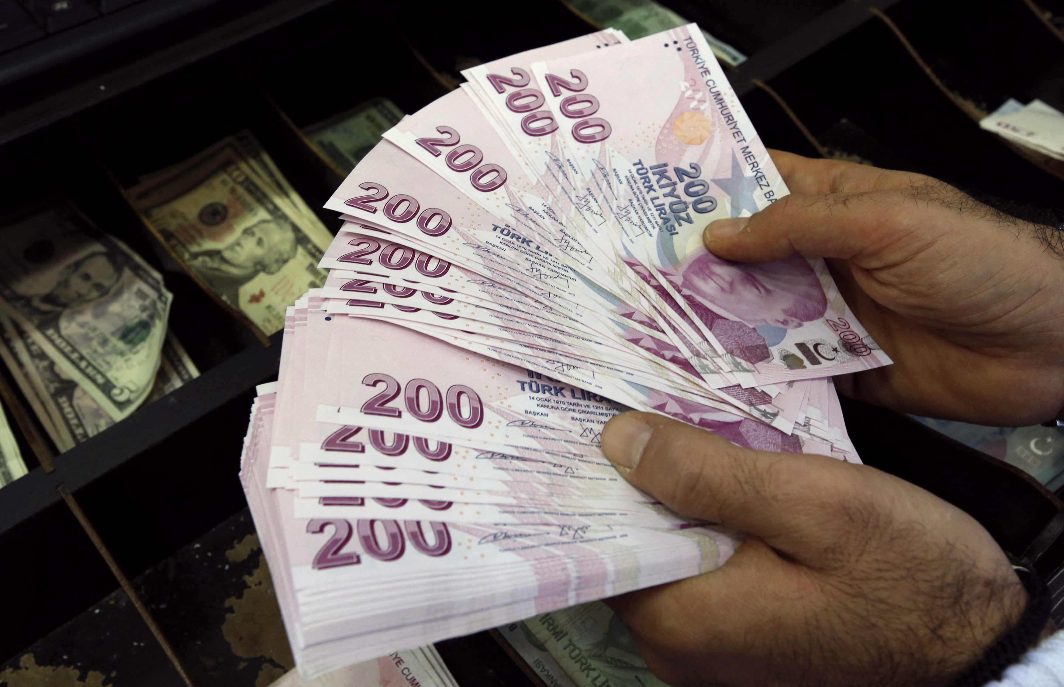 A money changer counts Turkish lira bills at an currency exchange office in Istanbul