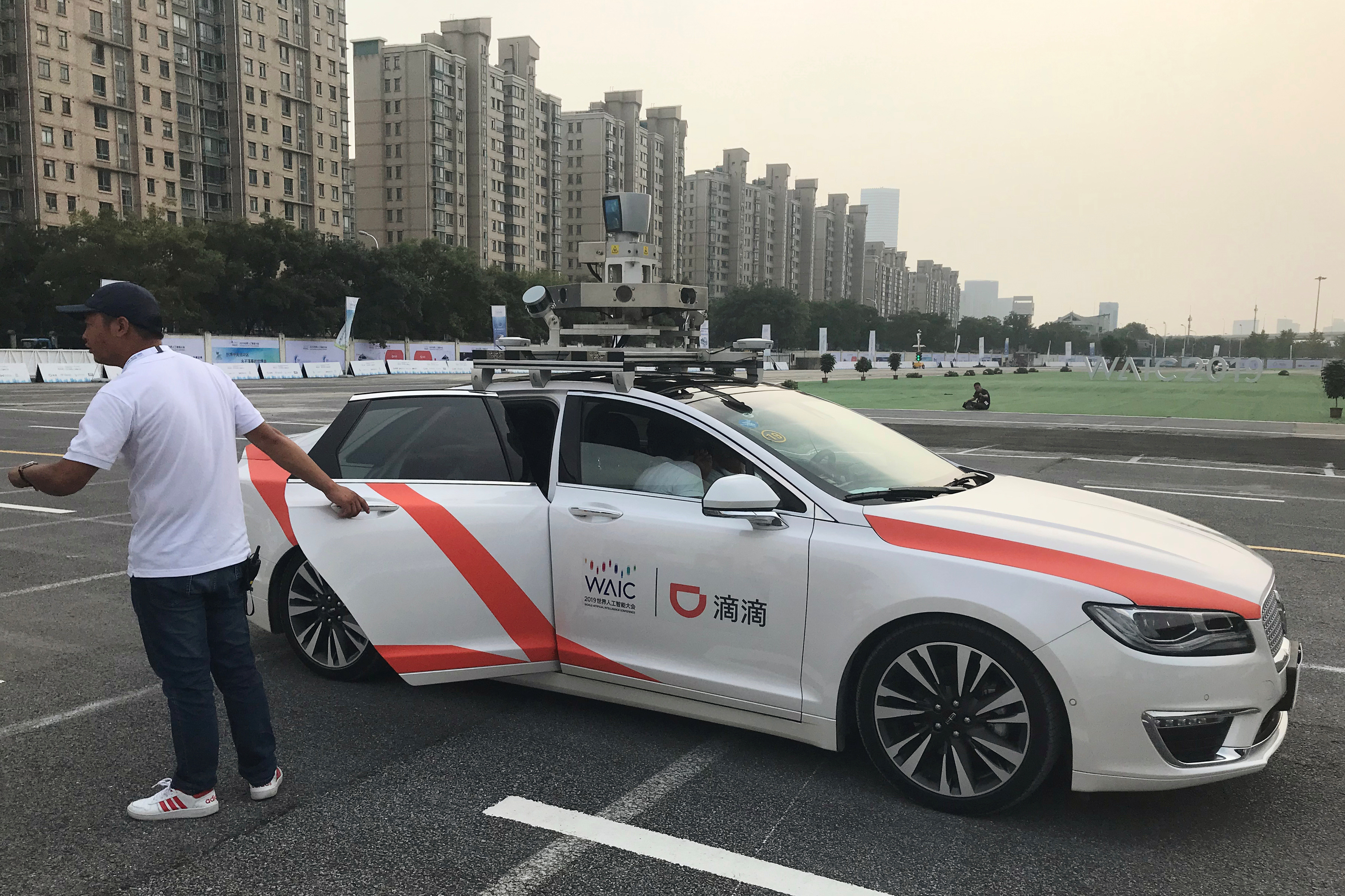 Man holds a door to a Didi self-driving car during the World Artificial Intelligence Conference (WAIC) in Shanghai