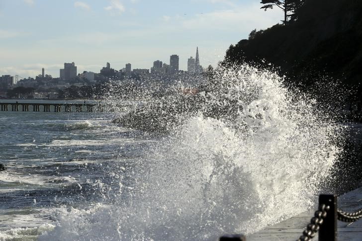 Waves crash against a sea wall in San Francisco Bay near the Golden Gate Bridge in San Francisco