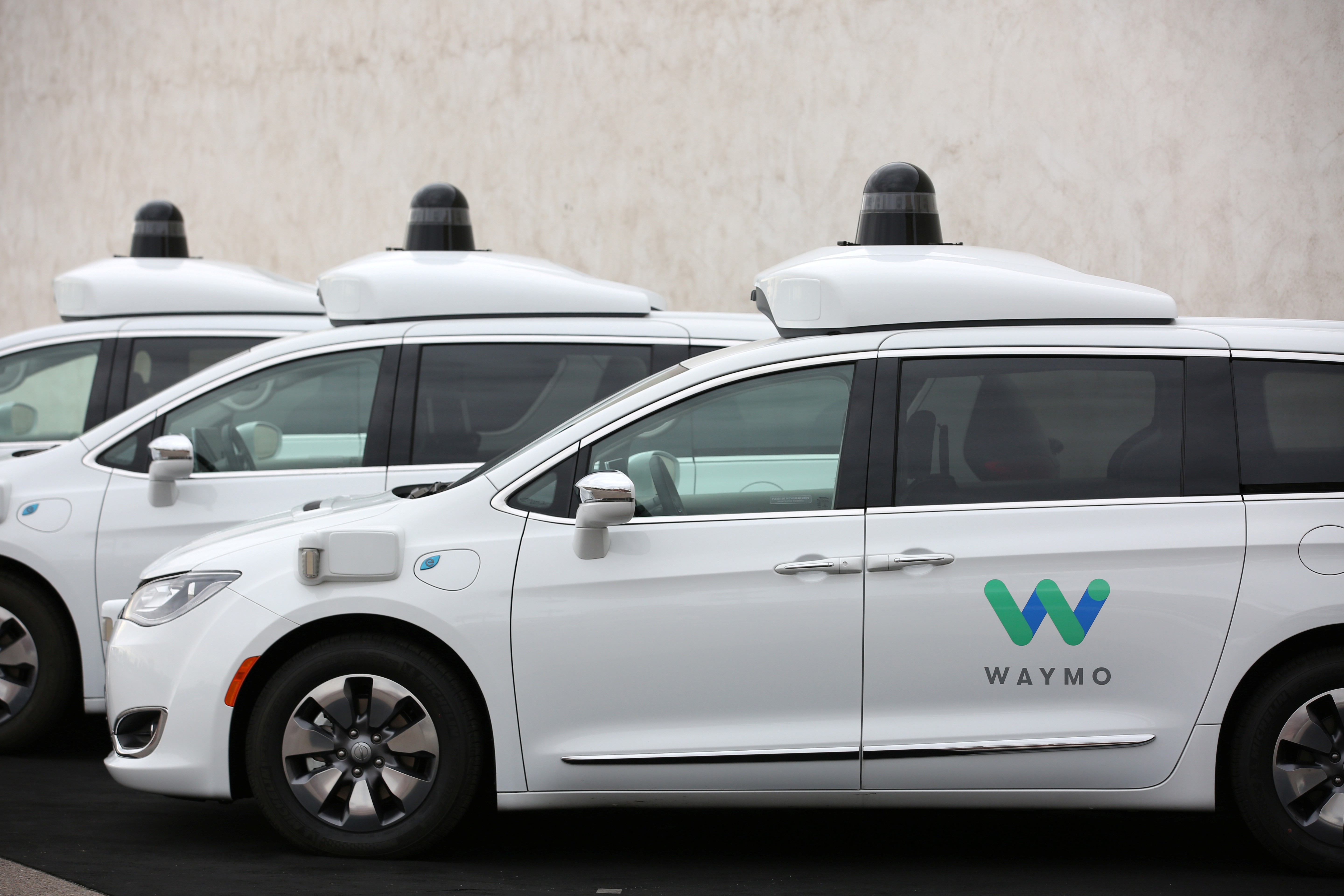 Three of the fleet of 600 Waymo Chrysler Pacifica Hybrid self-driving vehicles are parked and diaplayed during a demonstration in Chandler, Arizona