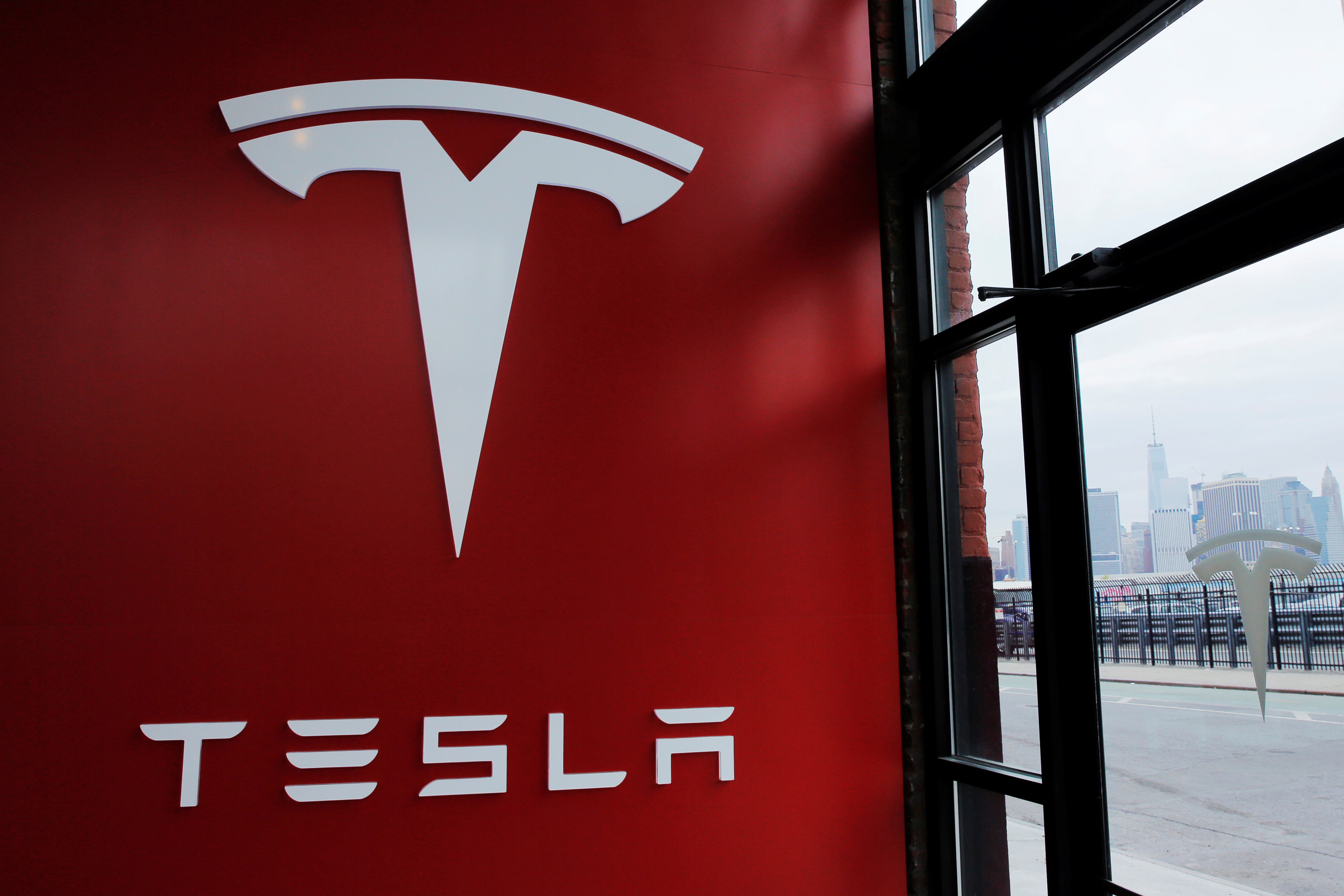 A Tesla logo is painted on a wall inside of a Tesla dealership in New York