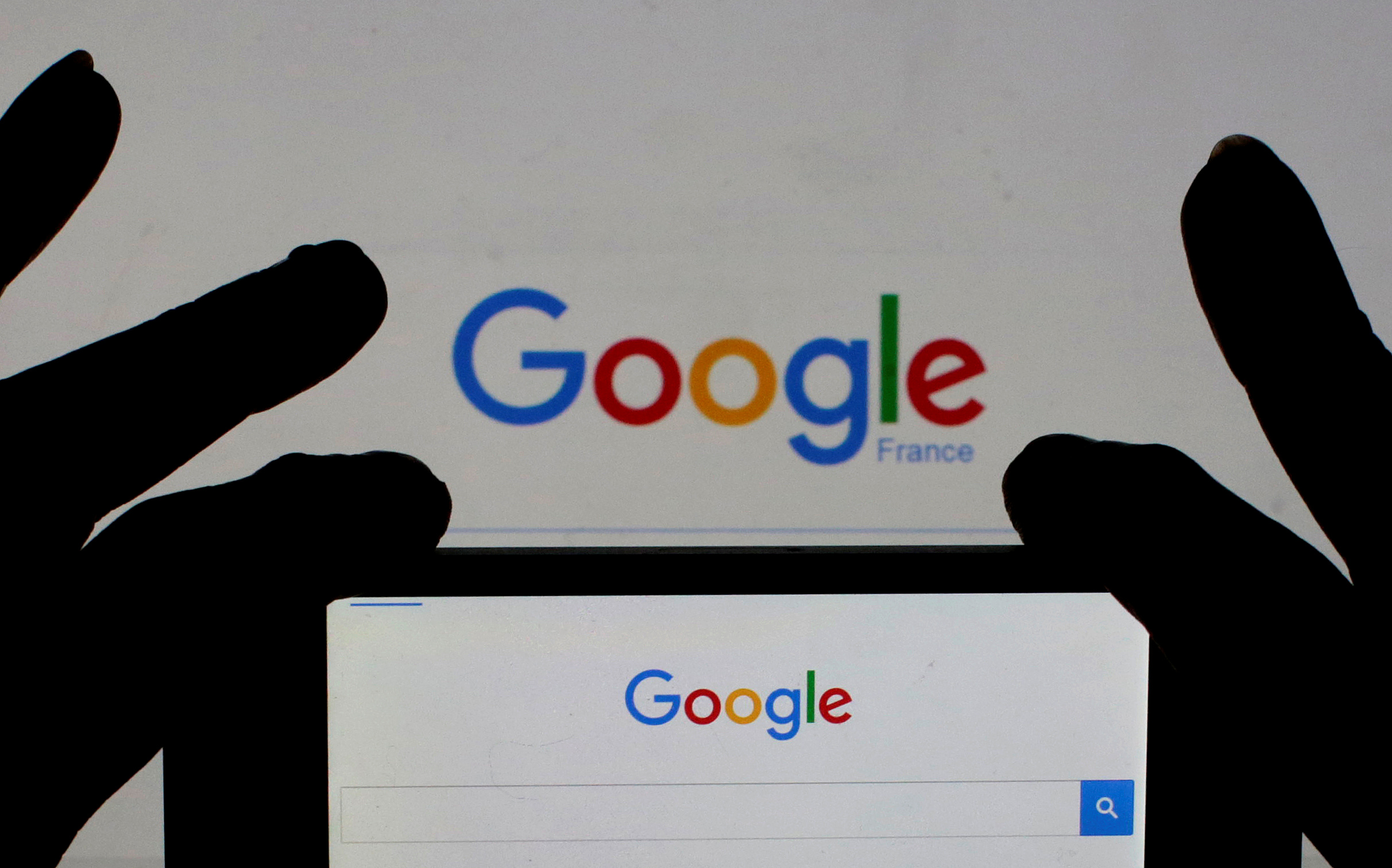 File photo of a woman holding her smart phone which displays the Google home page, in this picture illustration