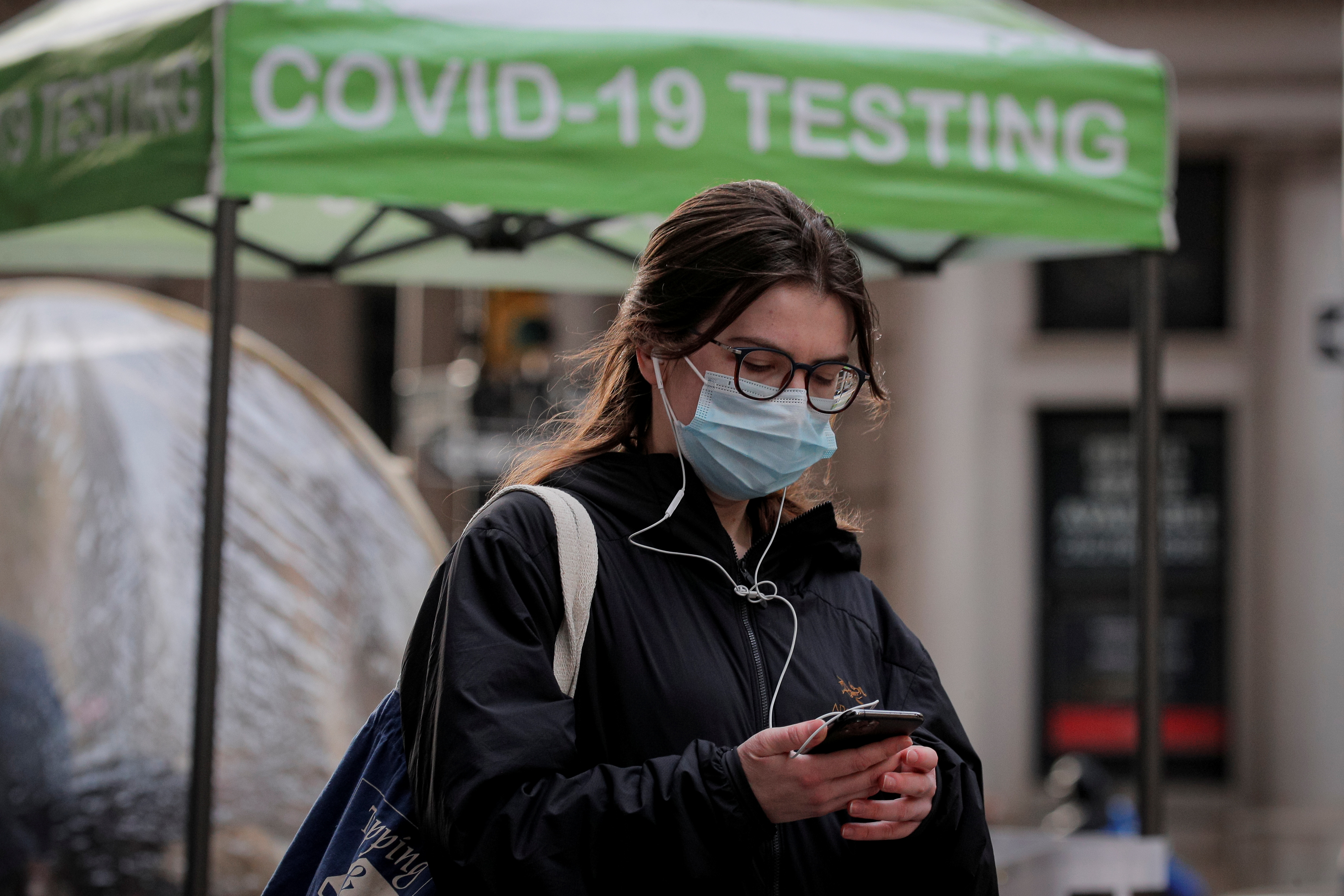A woman uses her phone outside a coronavirus disease (COVID-19) sidewalk testing site in New York