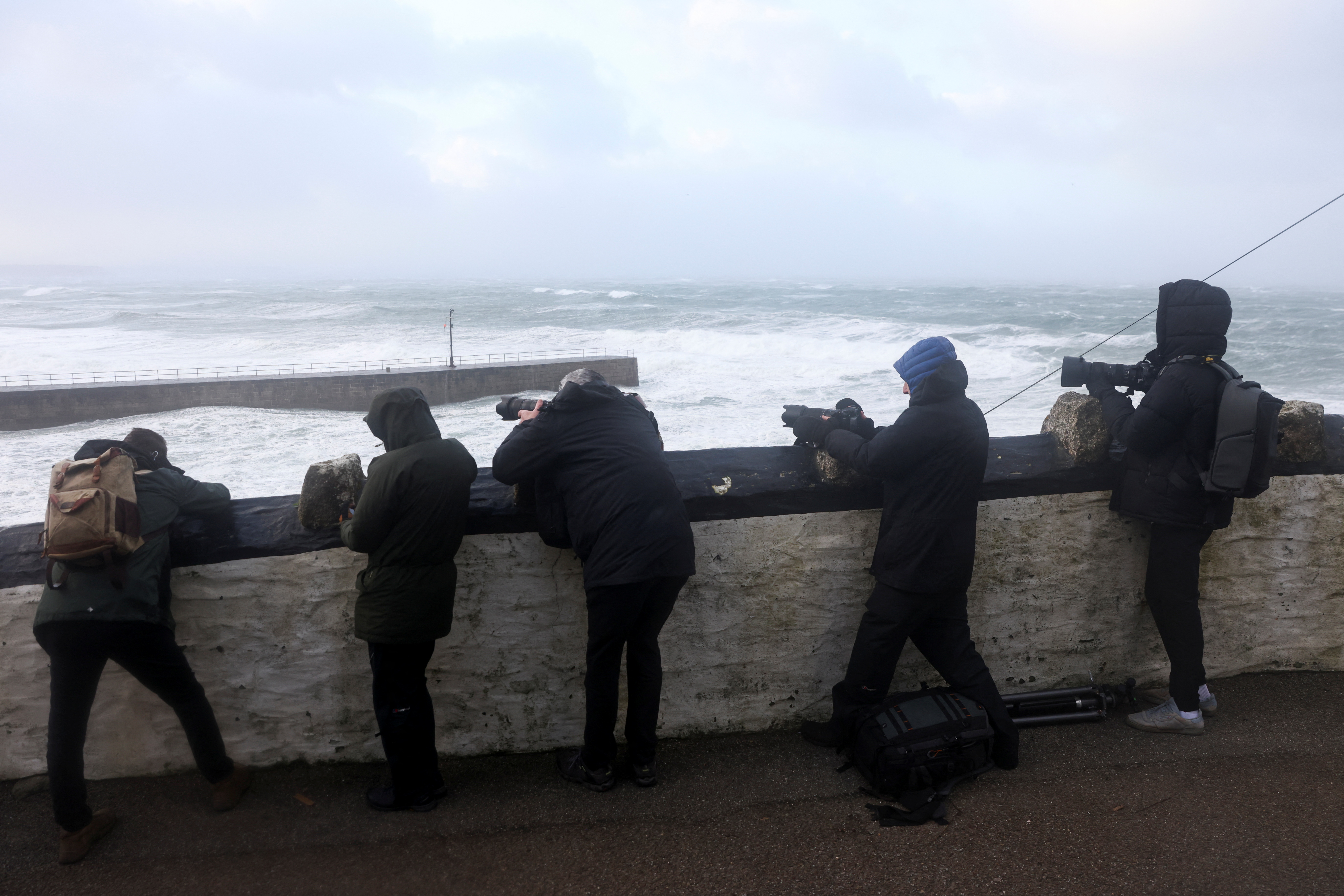 Photographers take pictures as large waves and strong winds hit during Storm Eunice, in Porthleven, Cornwall, Britain, February 18, 2022. REUTERS/Tom Nicholson