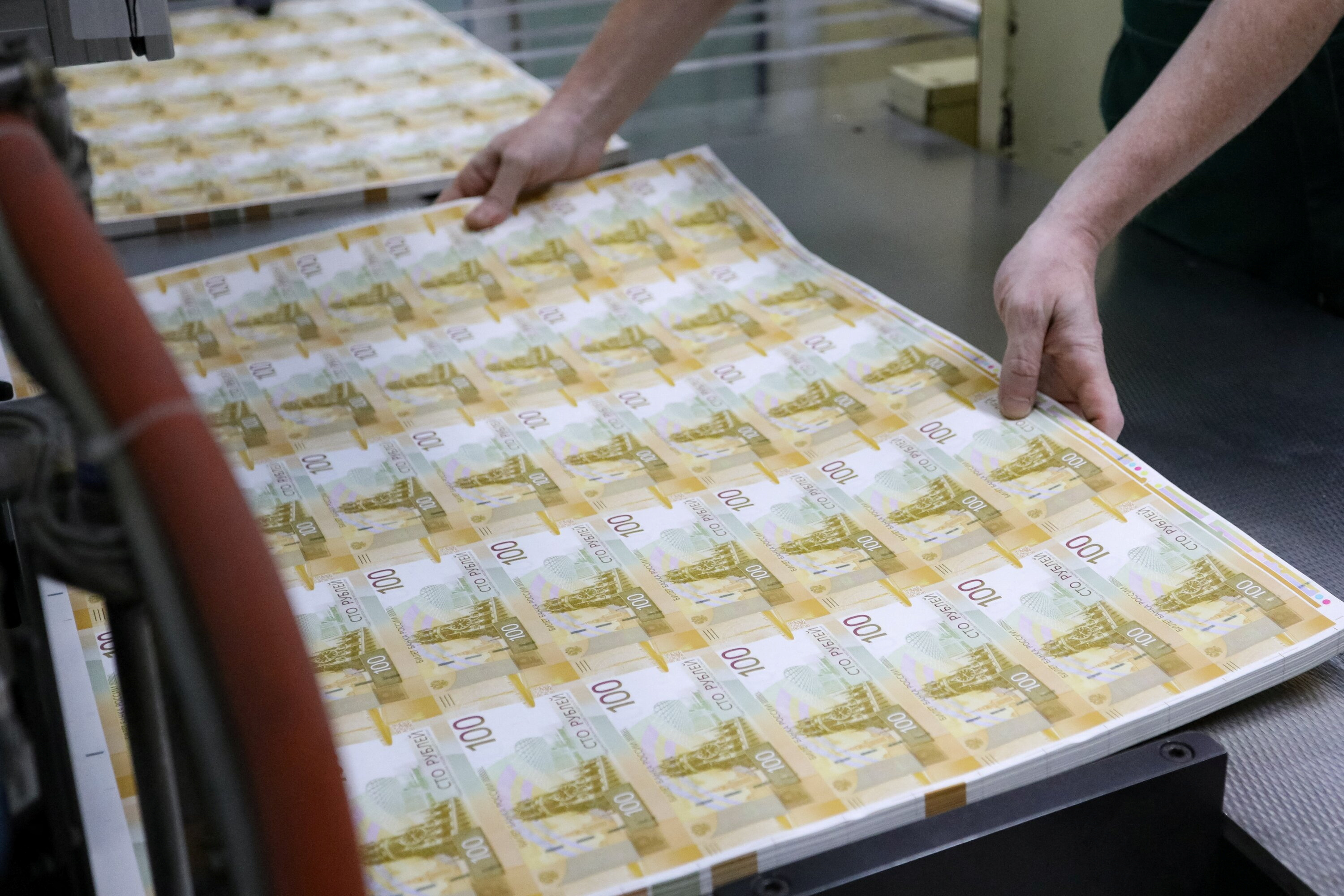 An employee holds sheets of the newly designed Russian 100-rouble banknotes at Goznak printing factory in Moscow