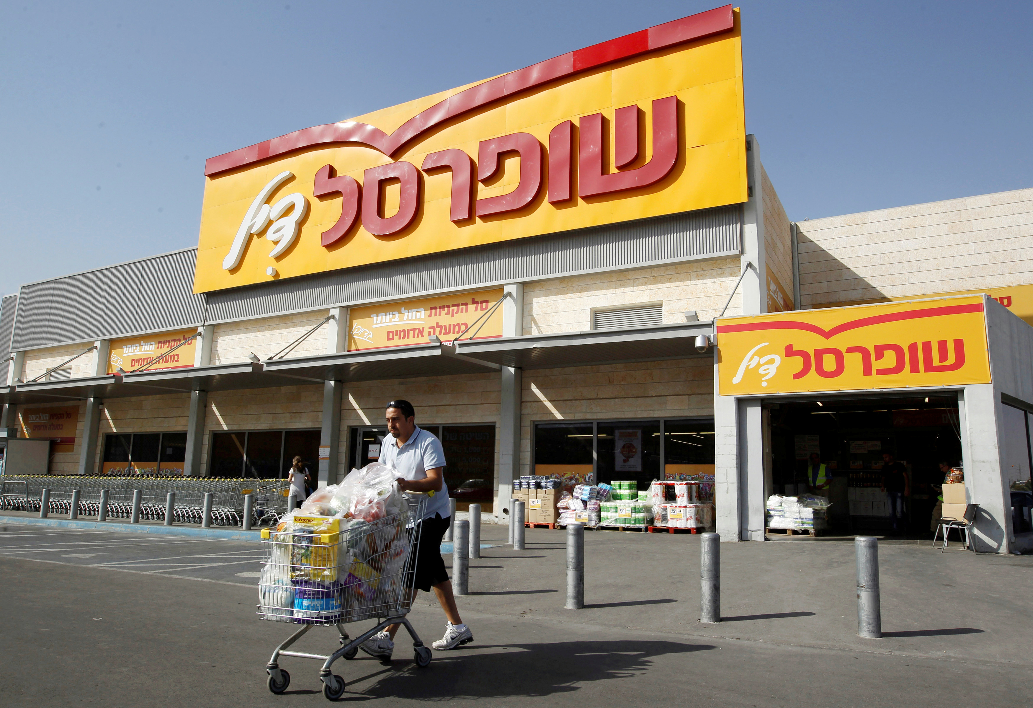 A man pushes a shopping cart outside Shufersal in the West Bank Jewish settlement of Mishor Adumim near Jerusalem
