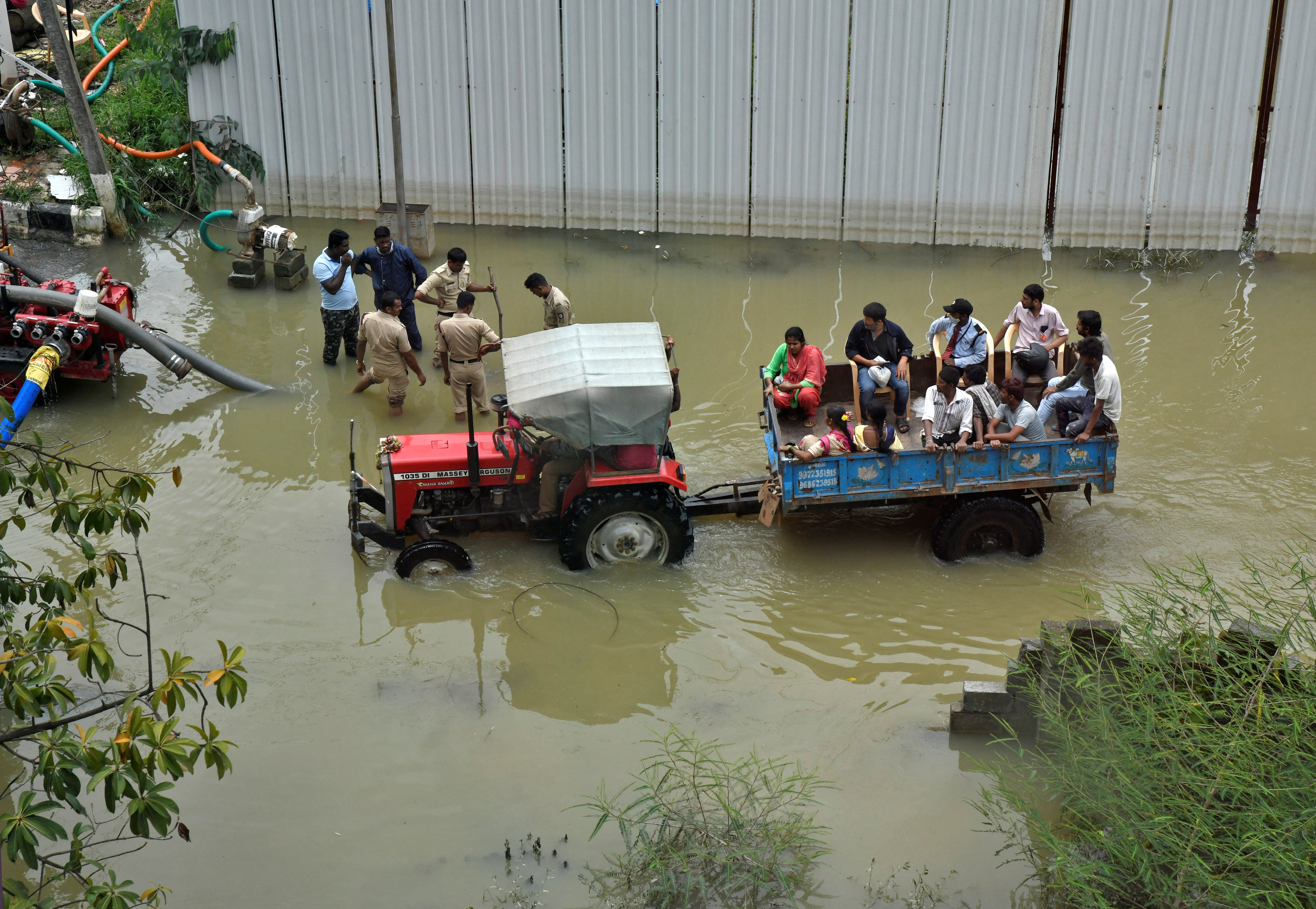 People commute in a tractor trolley through a water-logged neighbourhood following torrential rains in Bengaluru