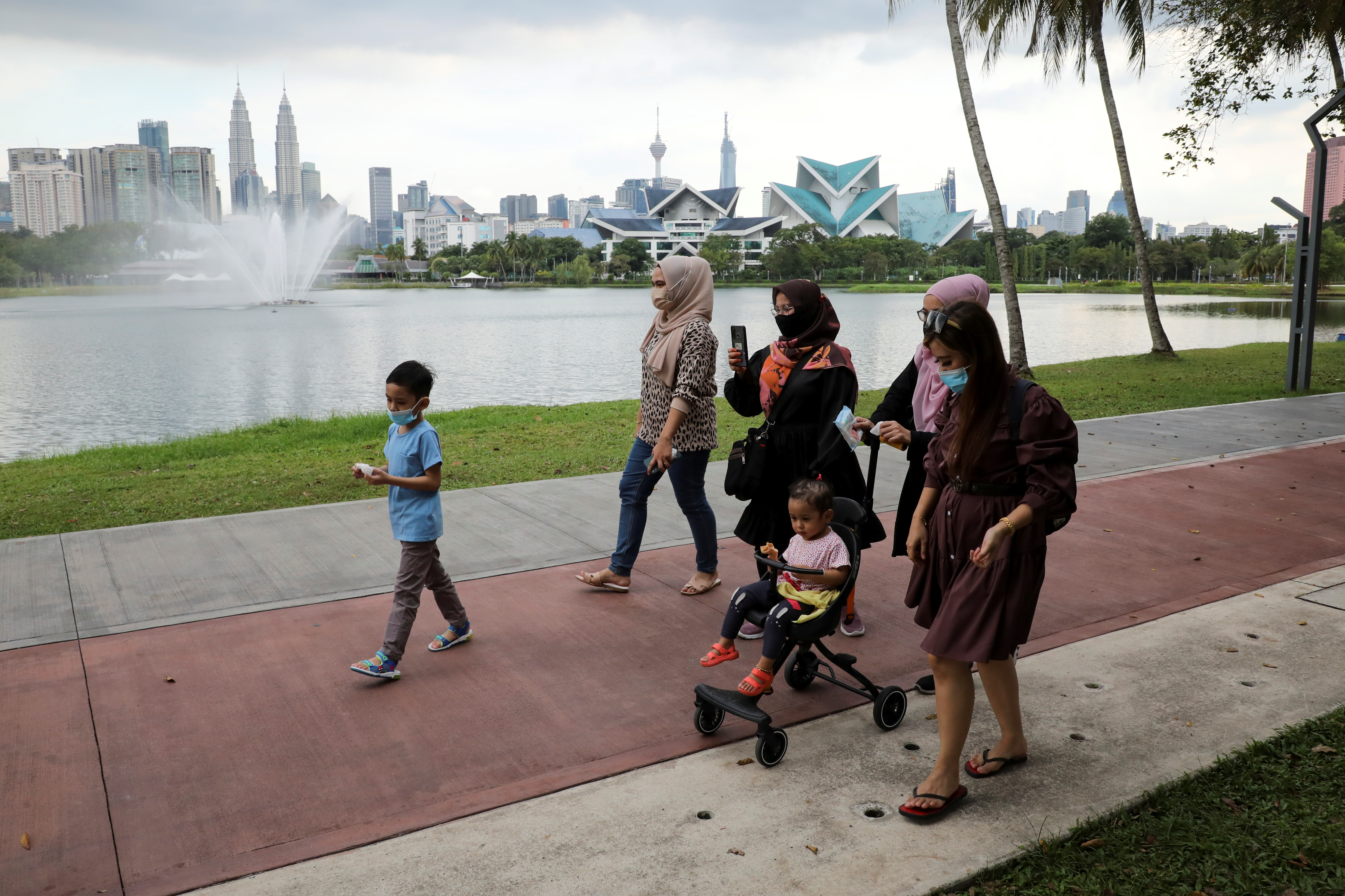 People wearing protective masks walk at a park, amid the coronavirus disease (COVID-19) pandemic, in Kuala Lumpur