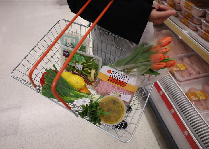 A customer carries a basket filled with food inside a Sainsbury’s supermarket in London