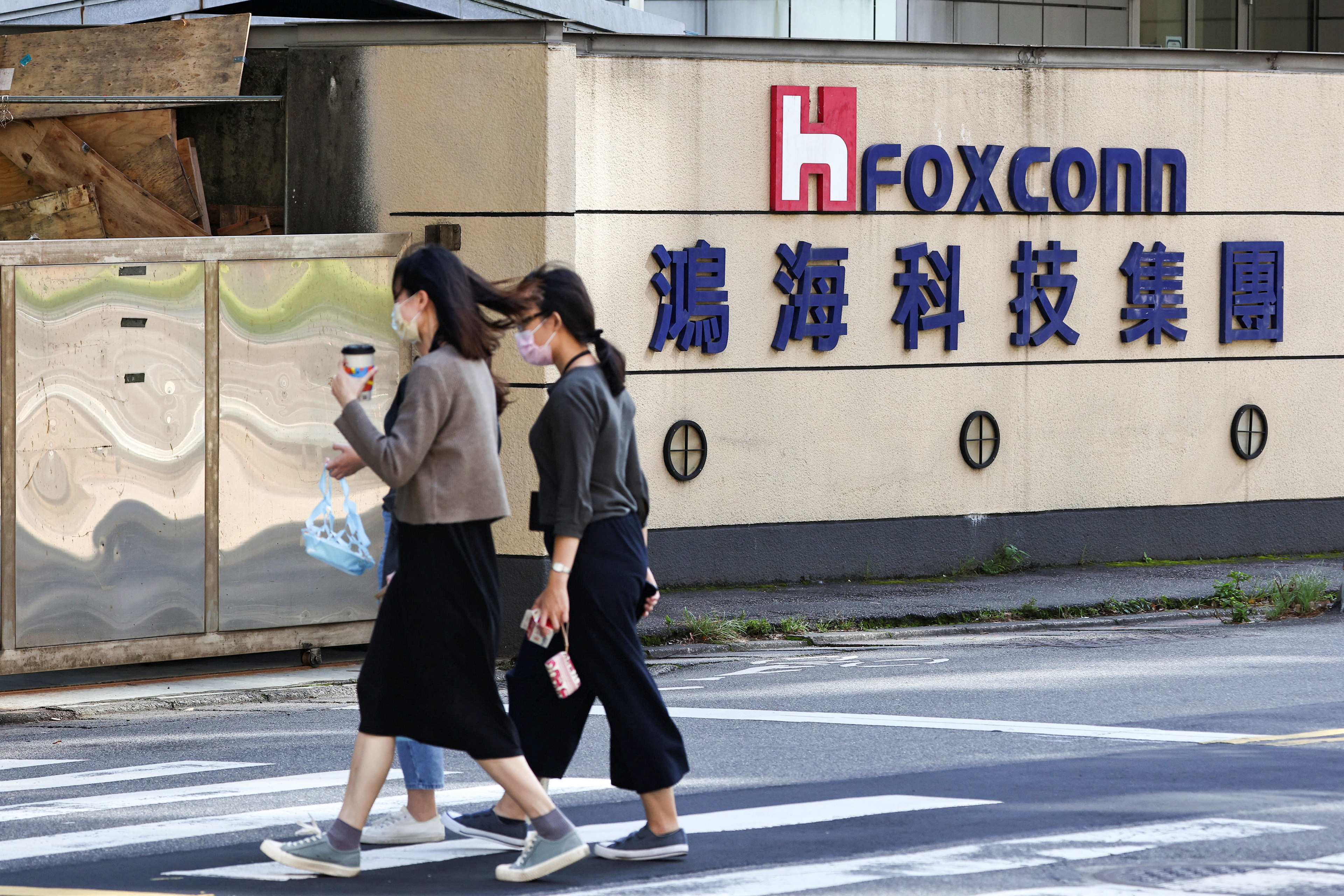 People walk past the logo of Foxconn outside the company's building in Taipei