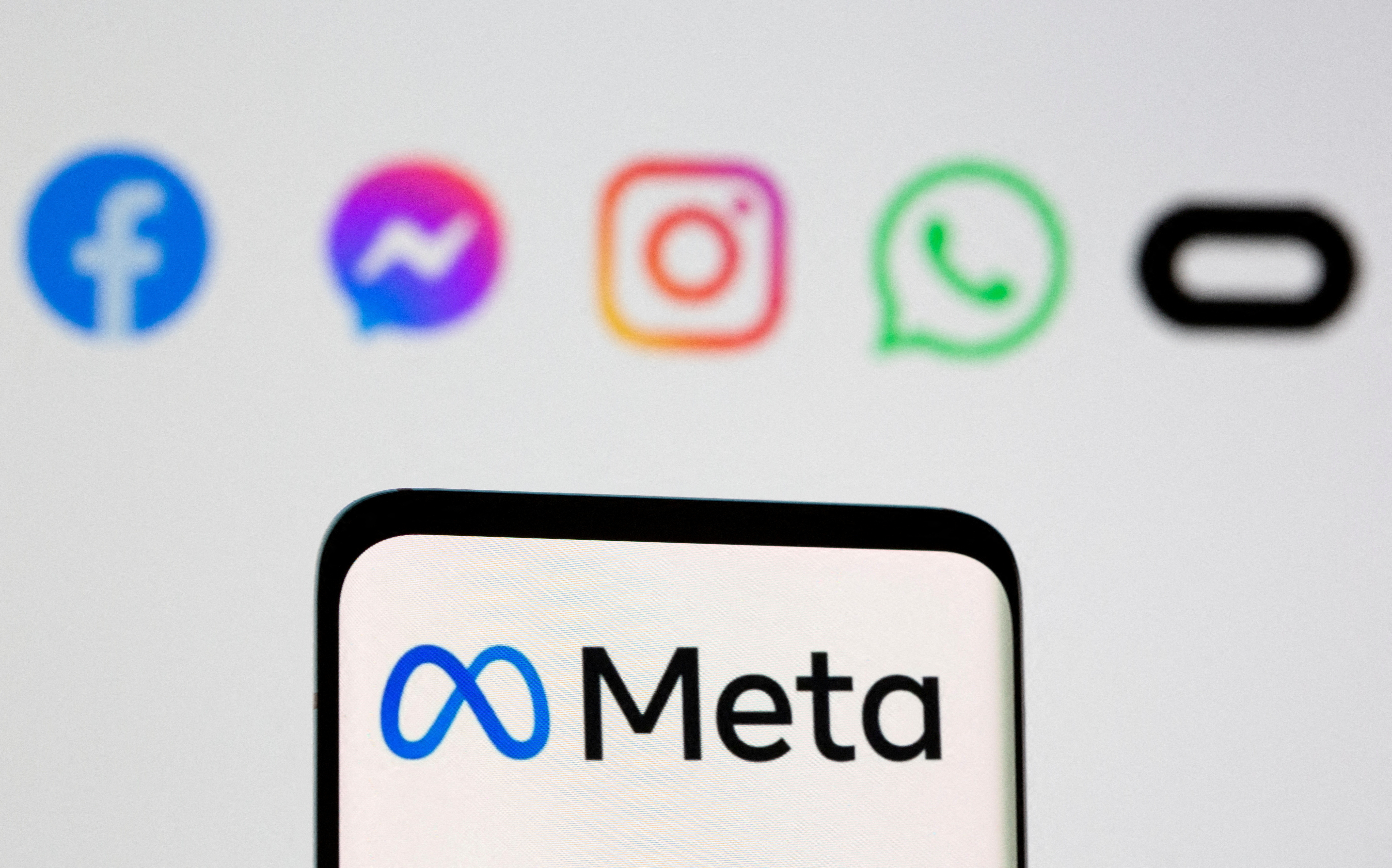 The Meta logo is seen on smartphone in front of displayed logo of Facebook, Messenger, Instagram, WhatsApp, Oculus in this illustration taken