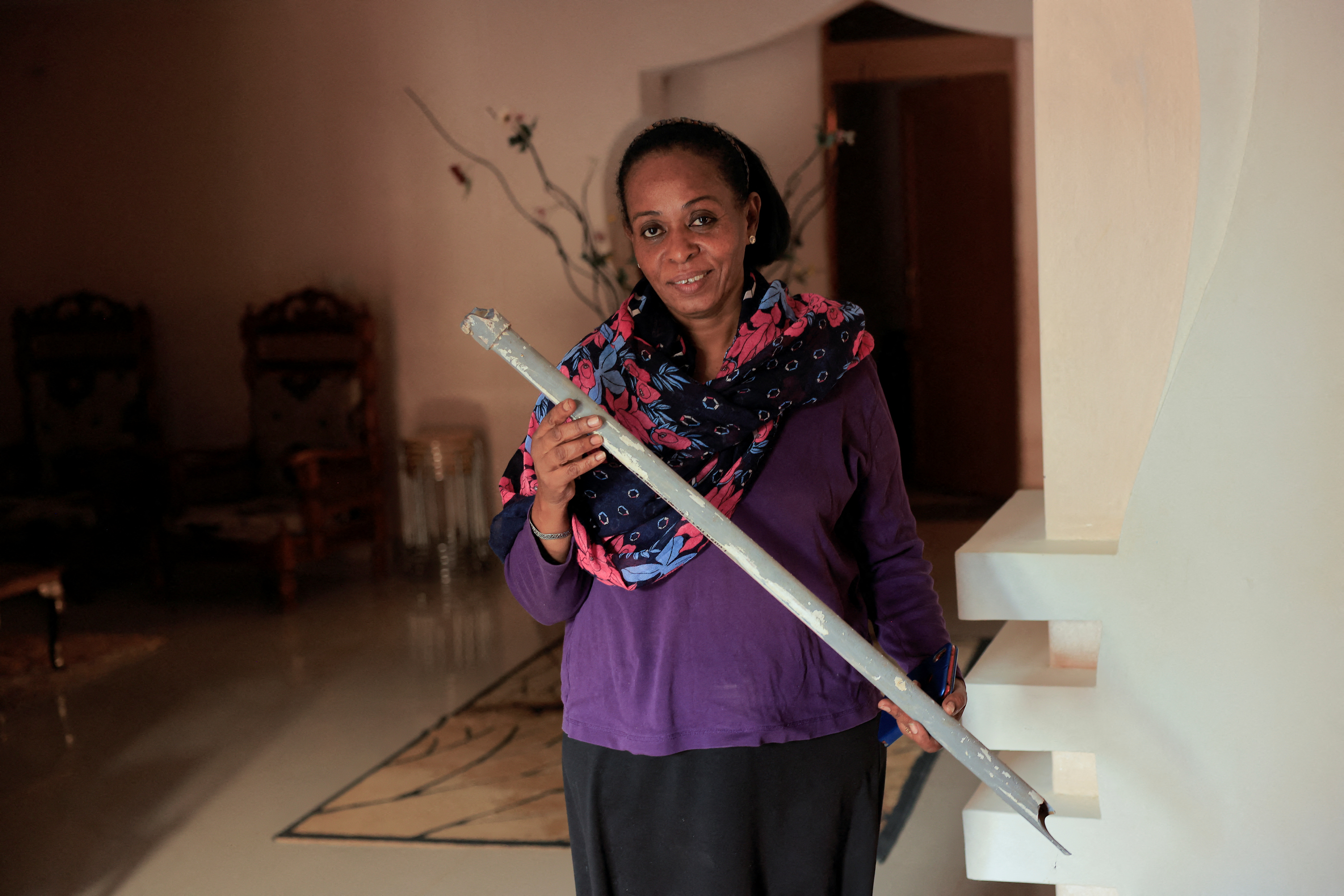 Amani sister of prominent Sudanese women's rights campaigner Amira Osman carry a stick left by security after arrest in her home in Khartoum
