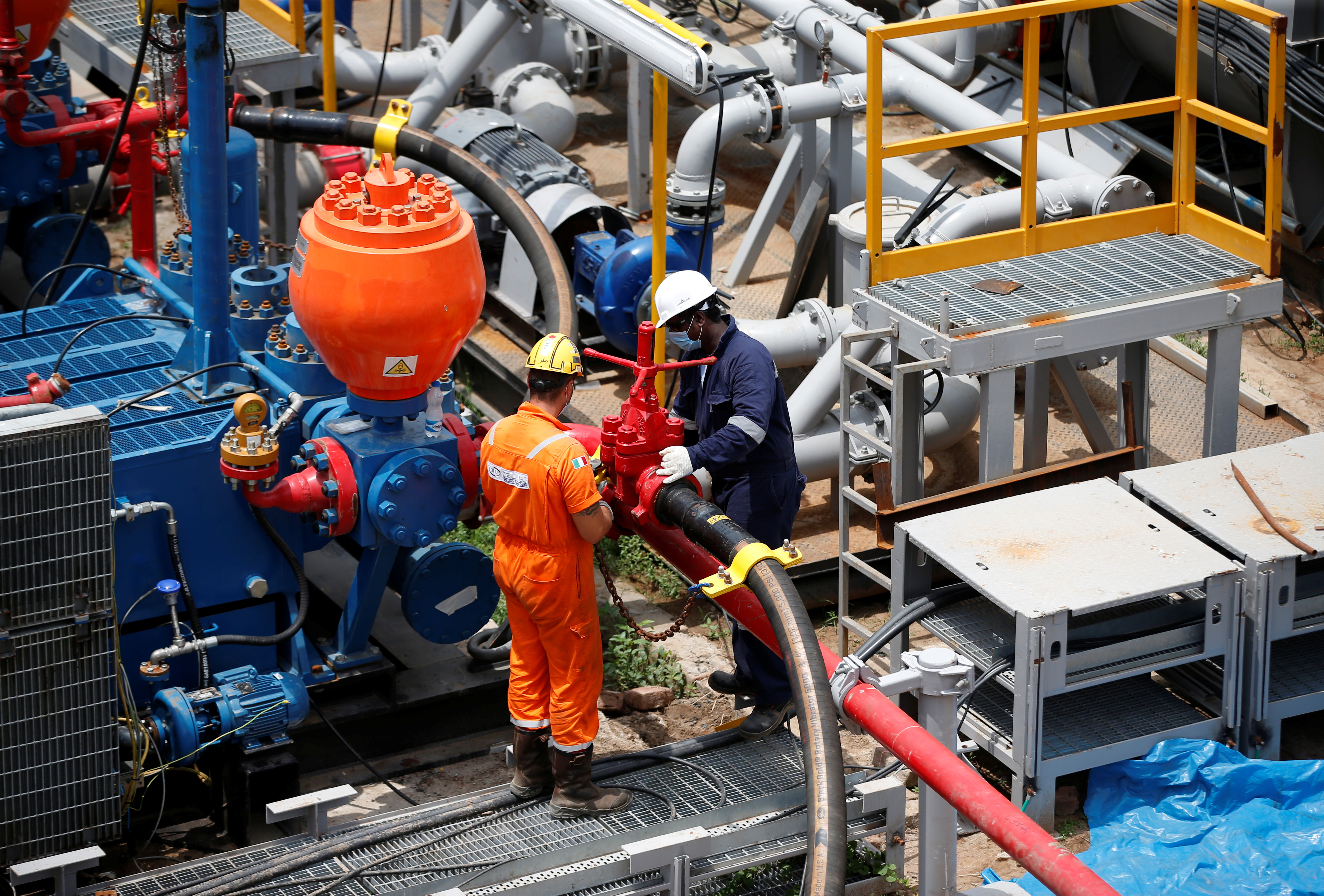 Technicians work at an oil rig manufactured by Megha Engineering and Infrastructures Limited (MEIL) at an Oil and Natural Gas Corp (ONGC) plant, during a media tour of the plant in Dhamasna