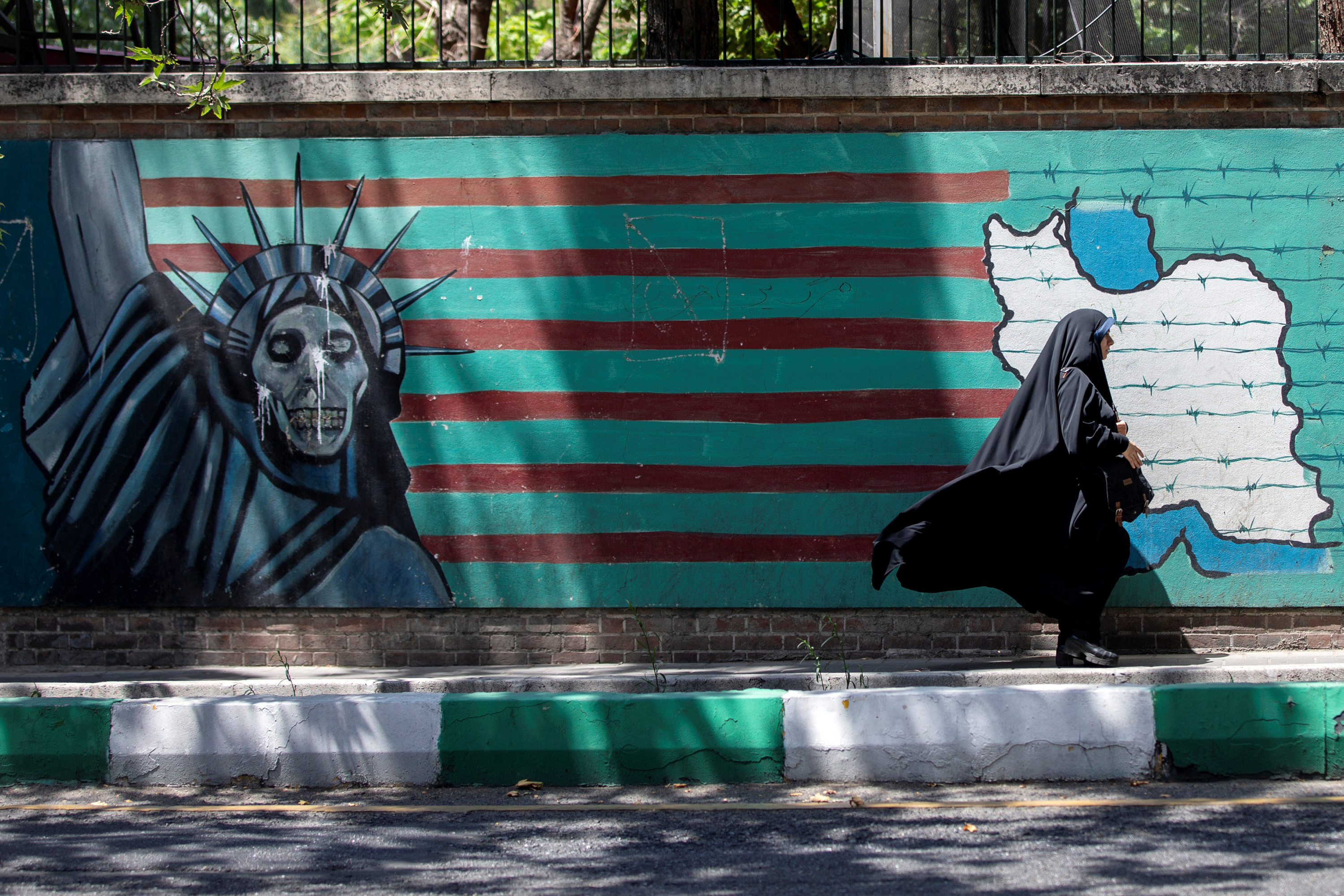A woman walks past the mural showing U.S. flag with barbed wire and the Statue Of Liberty with skull face in Tehran, Iran June 25, 2019.  Nazanin Tabatabaee/Nazanin Tabatabaee/West Asia News Agency via REUTERS/File Photo
