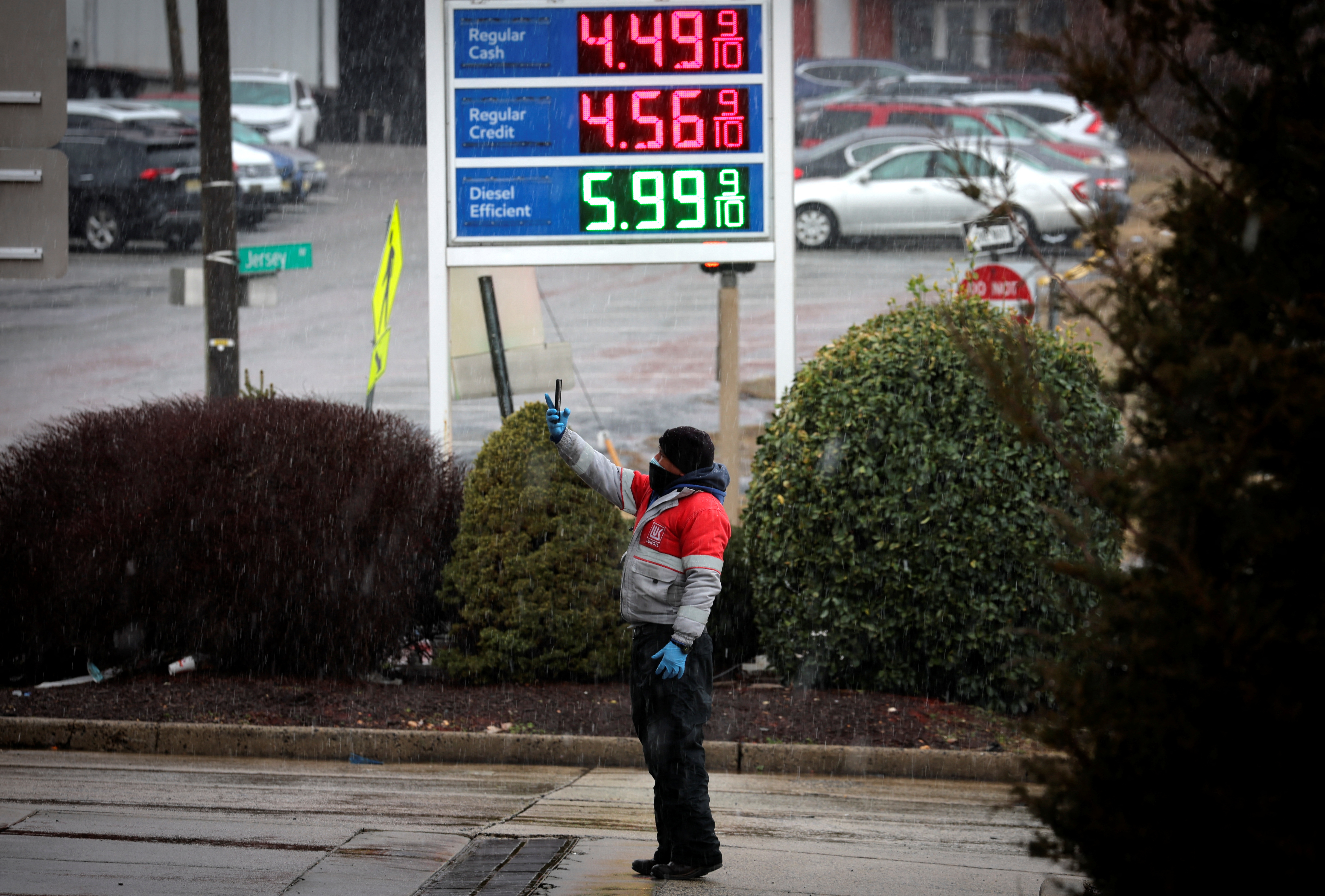 Worker takes pictures of gasoline prices at a gas station in Jersey City, New Jersey
