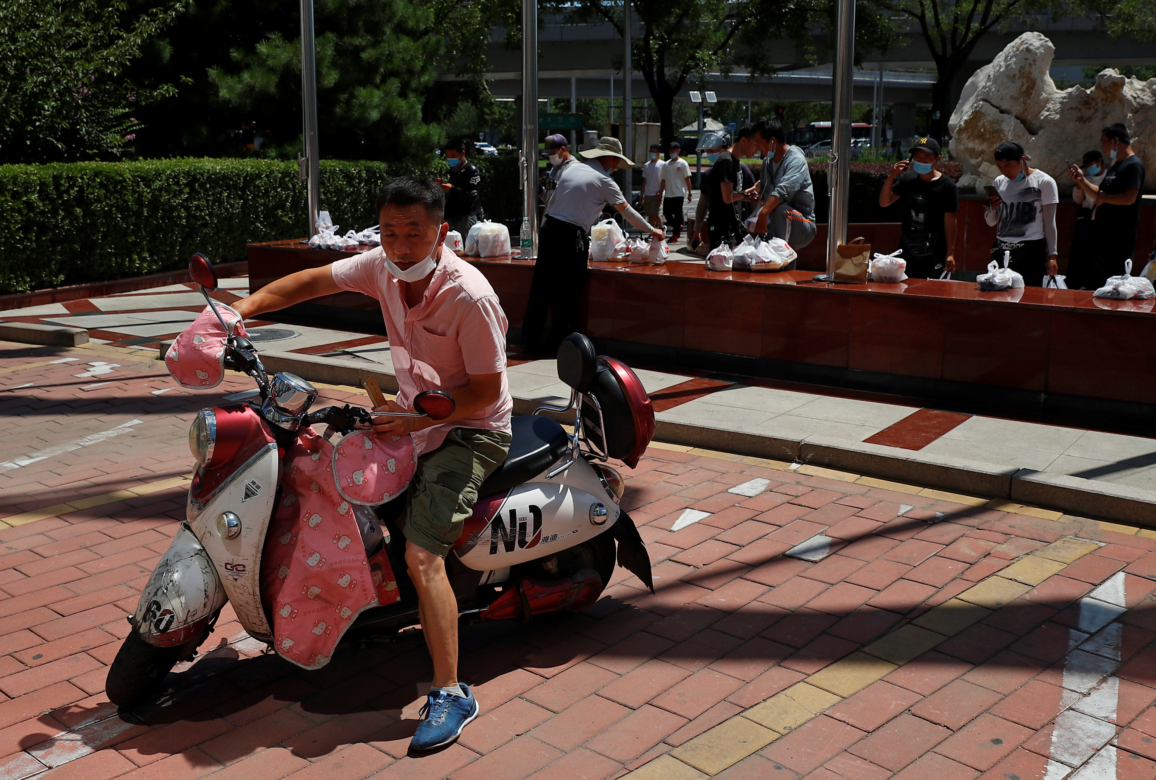 Food delivery drivers pick up their parcels at a makeshift lunch hour distribution spot following an outbreak of the coronavirus disease (COVID-19) in Beijing