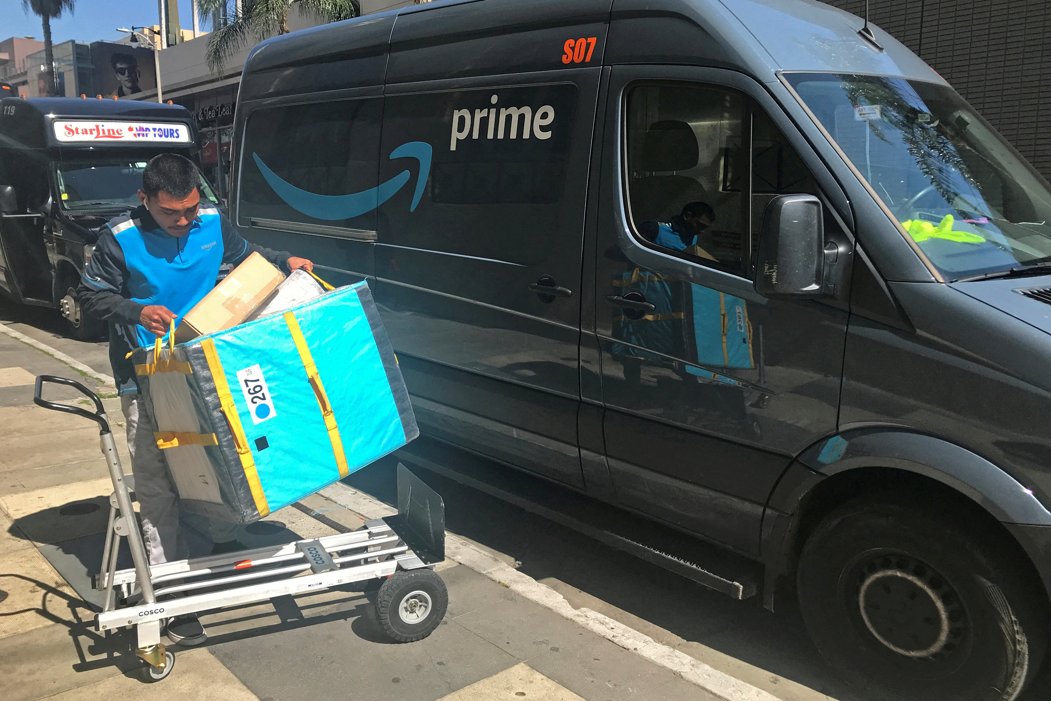 An Amazon delivery worker loads a trolley from a Prime van in Los Angeles