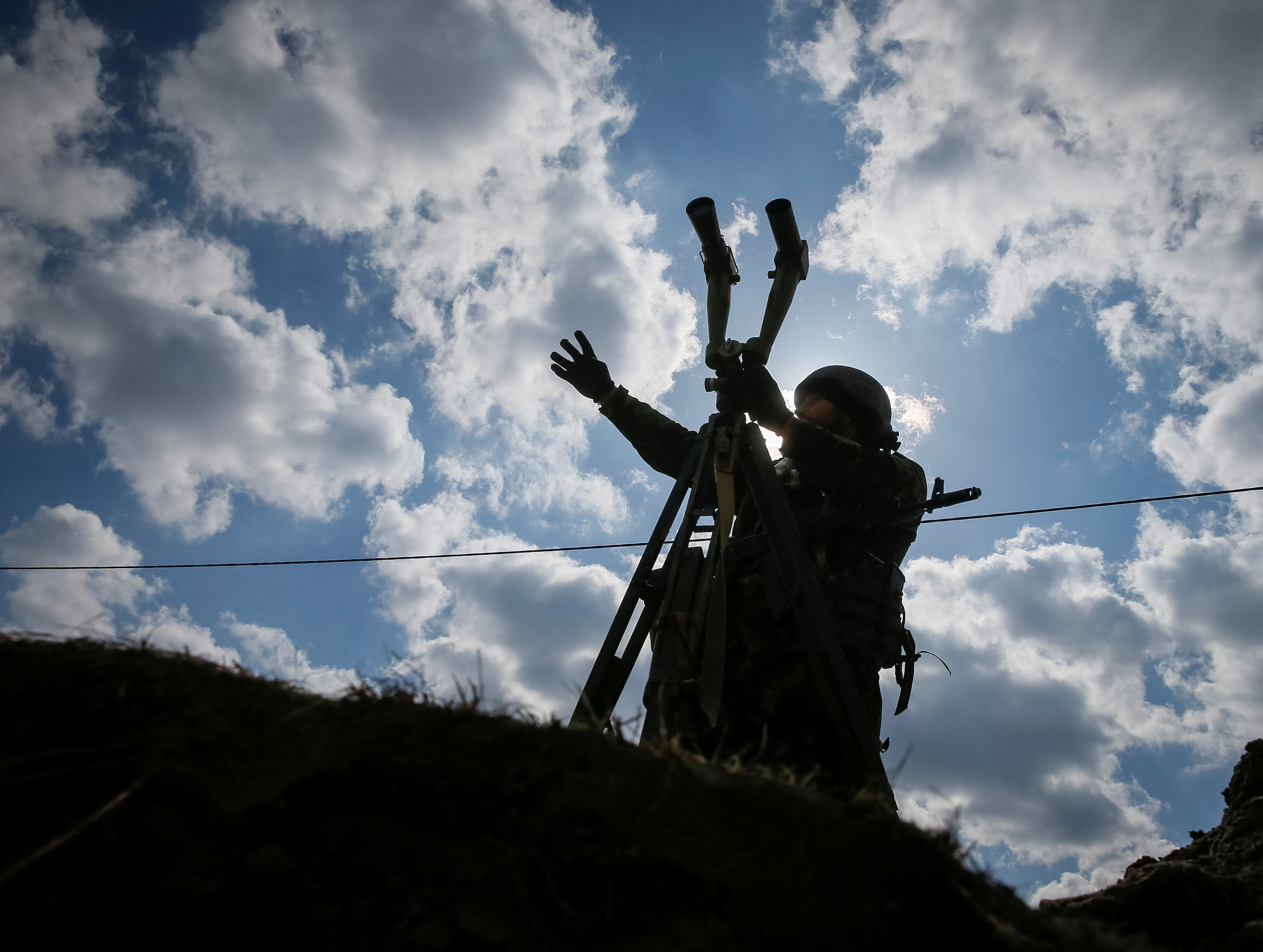 A Ukrainian service member uses binoculars at a position on the front line in the north Kyiv region