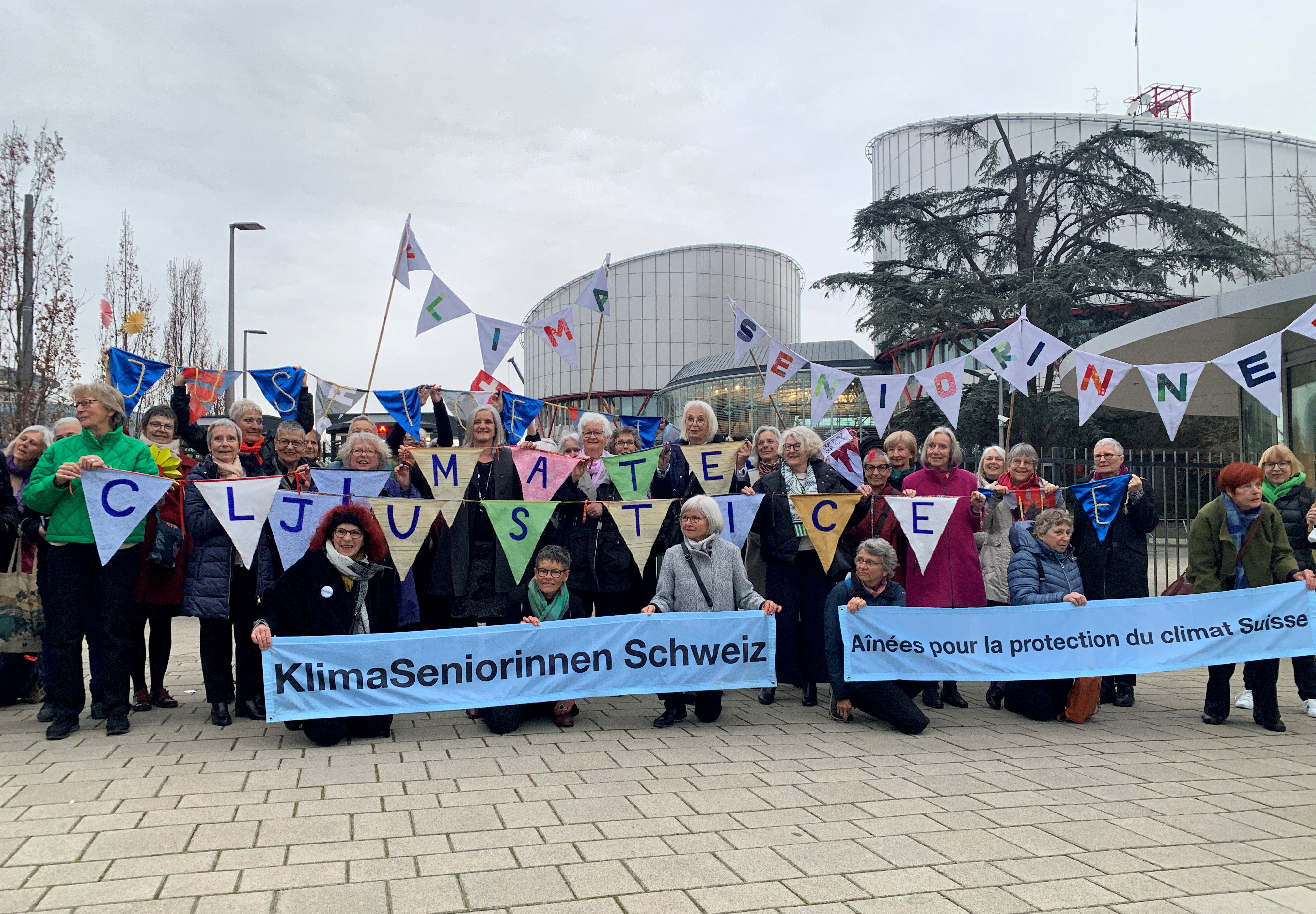 A group from the Senior Women for Climate Protection association hold banners outside the European Court of Human Rights in Strasbourg