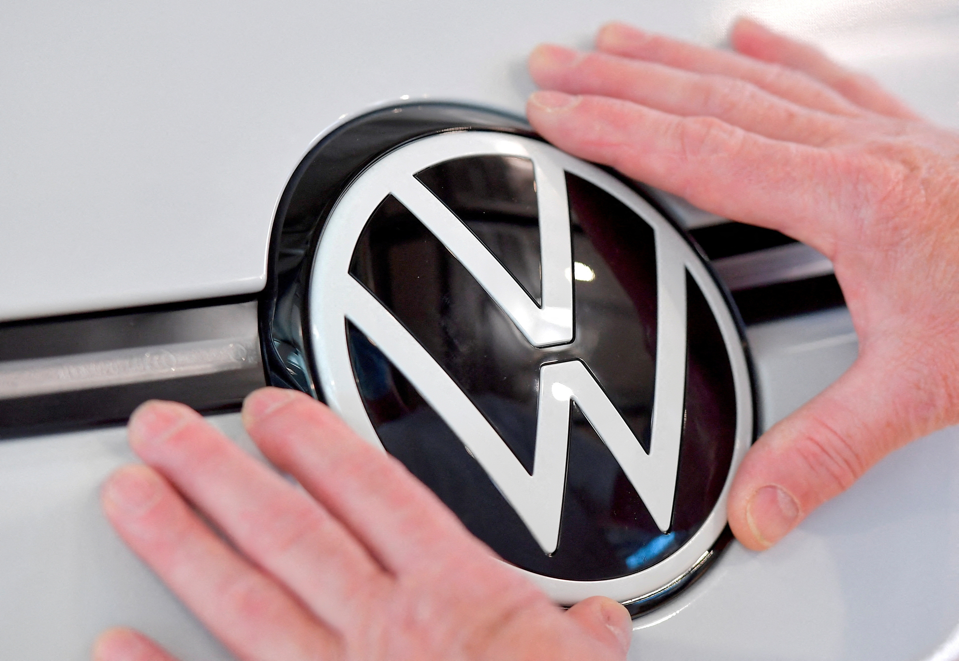 A technician fixes a VW sign in the assembly line of German carmaker Volkswagen's electric ID. 3