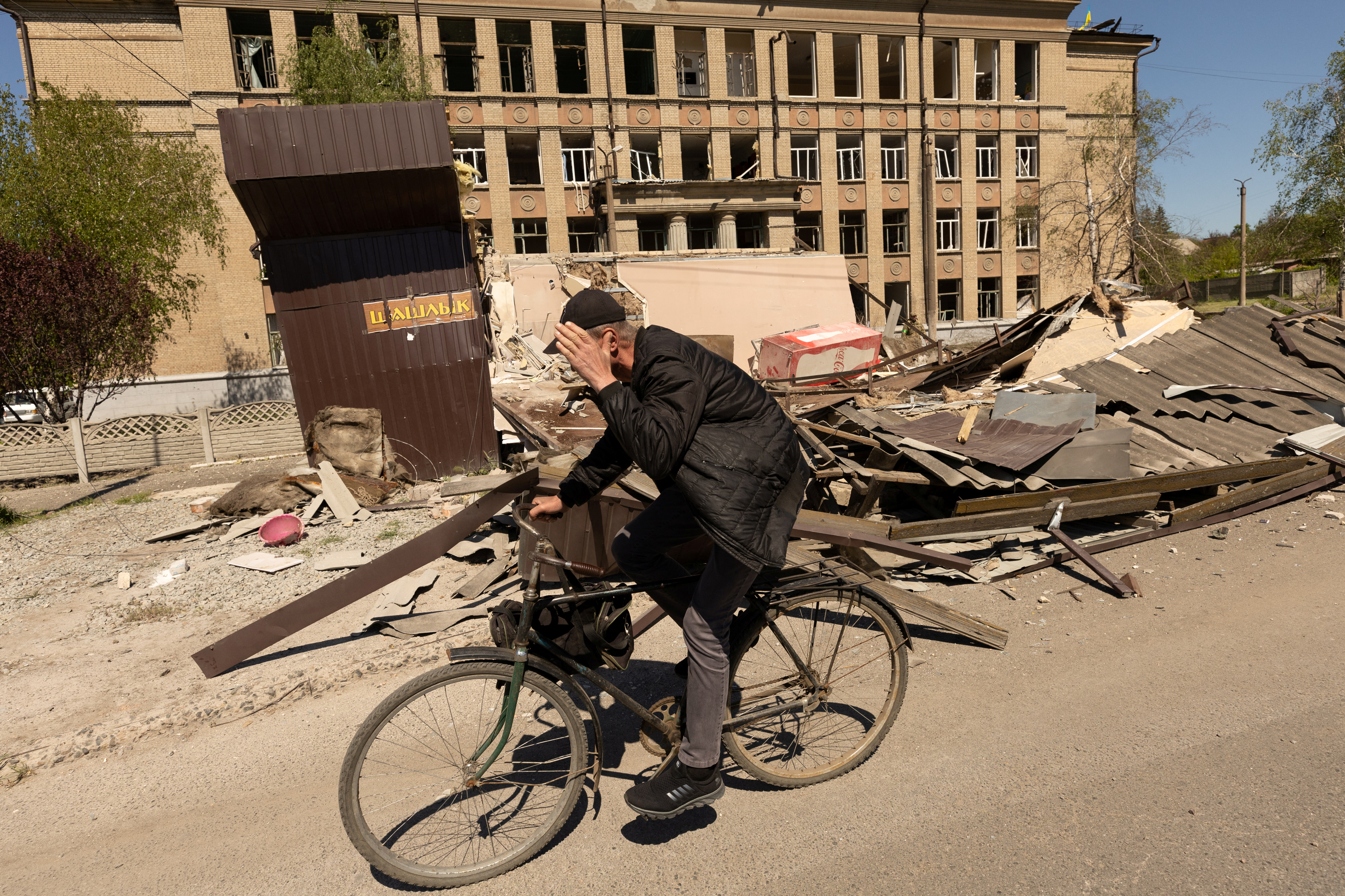 A man rides a bike in front of a school that was bombed amid Russia's invasion in Ukraine, in Kostyantynivka, in the Donetsk region