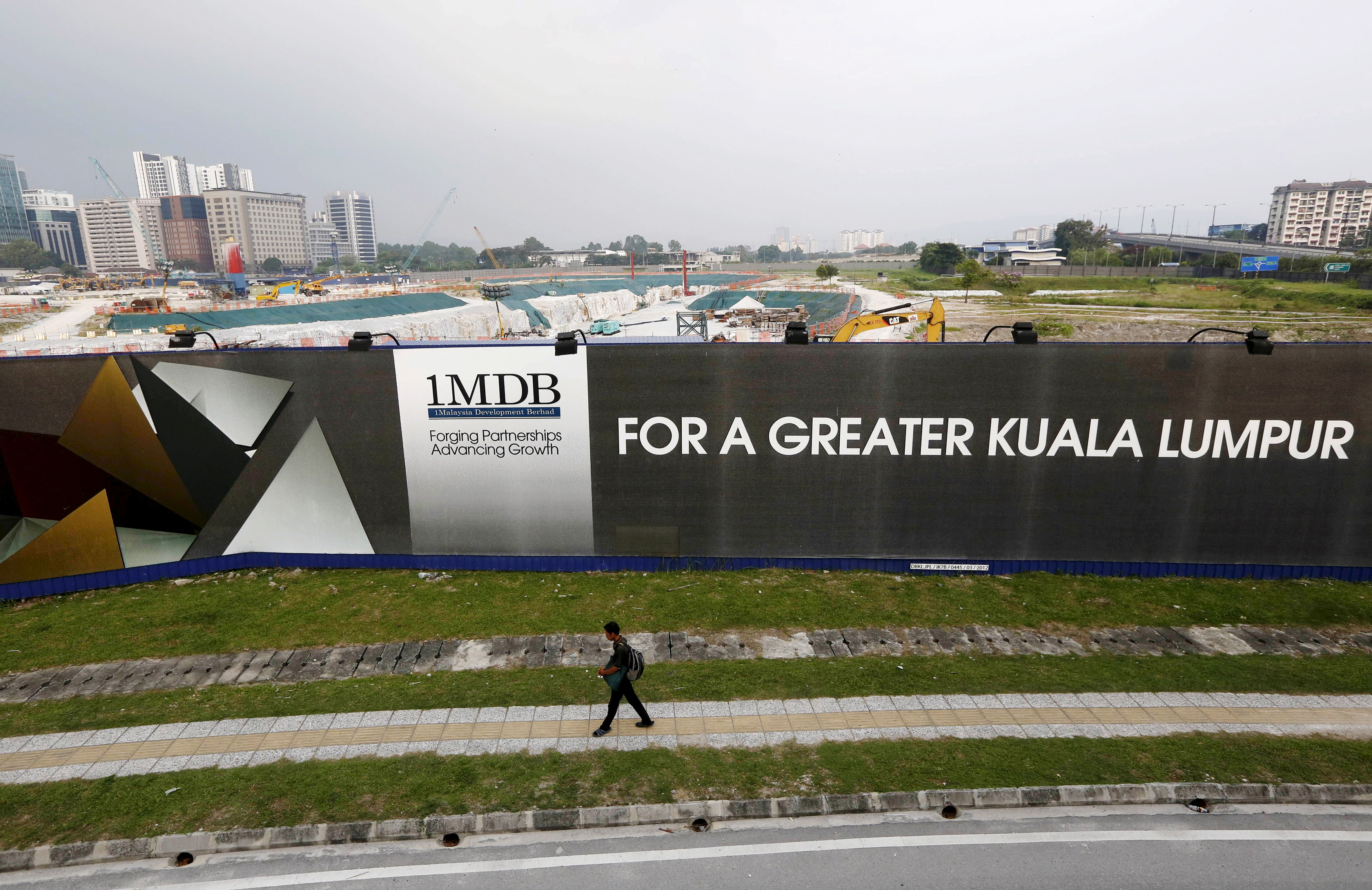 A man walks past a 1 Malaysia Development Berhad (1MDB) billboard at the funds flagship Tun Razak Exchange development in Kuala Lumpur