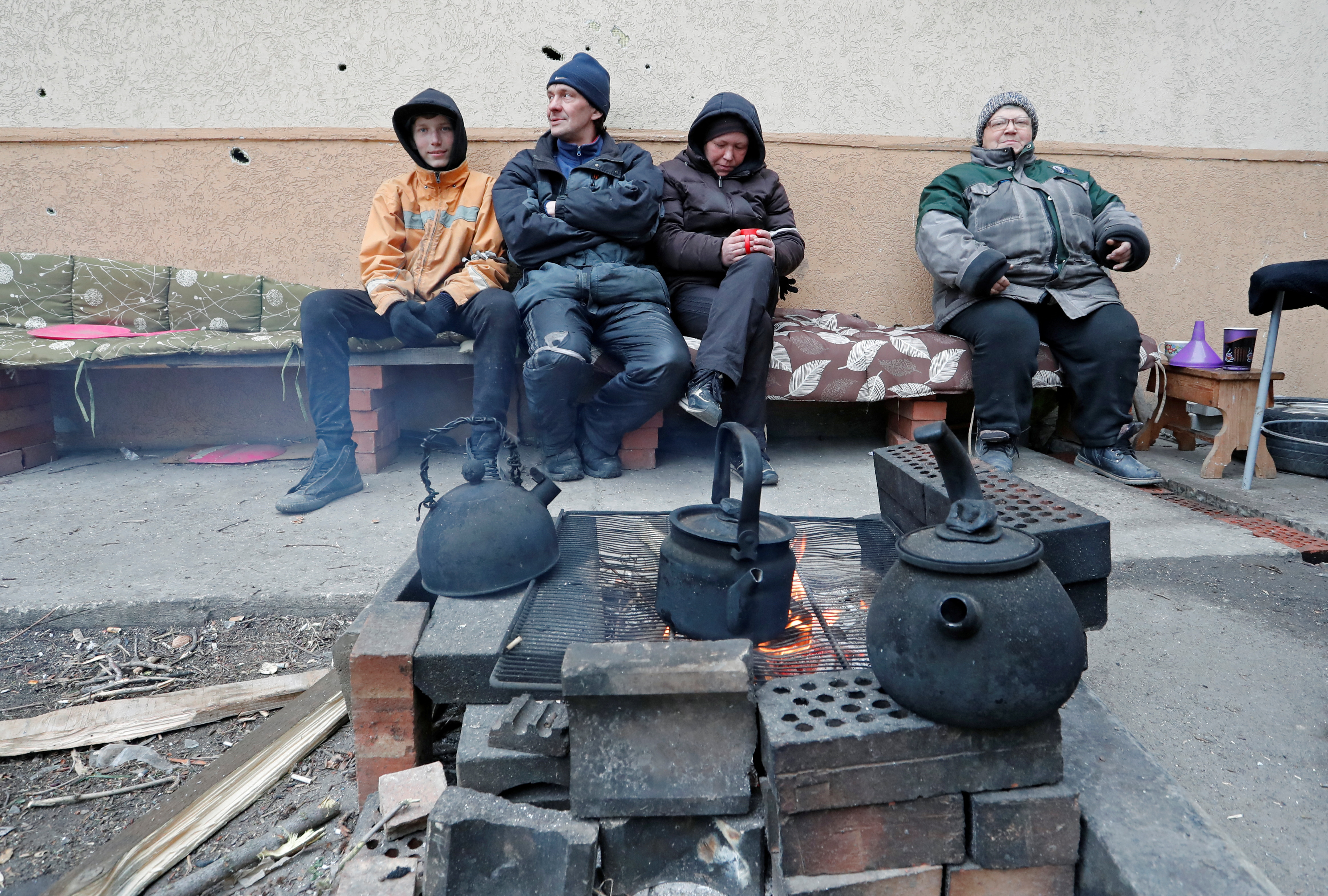 Local residents sit outside an apartment building in Mariupol