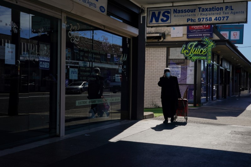 A woman wearing a protective face mask pulls a shopping trolley down the sidewalk during a lockdown to curb the spread of a coronavirus disease (COVID-19) outbreak in the Canterbury-Bankstown local government area of southwest Sydney, Australia, August 4, 2021. REUTERS/Loren Elliott