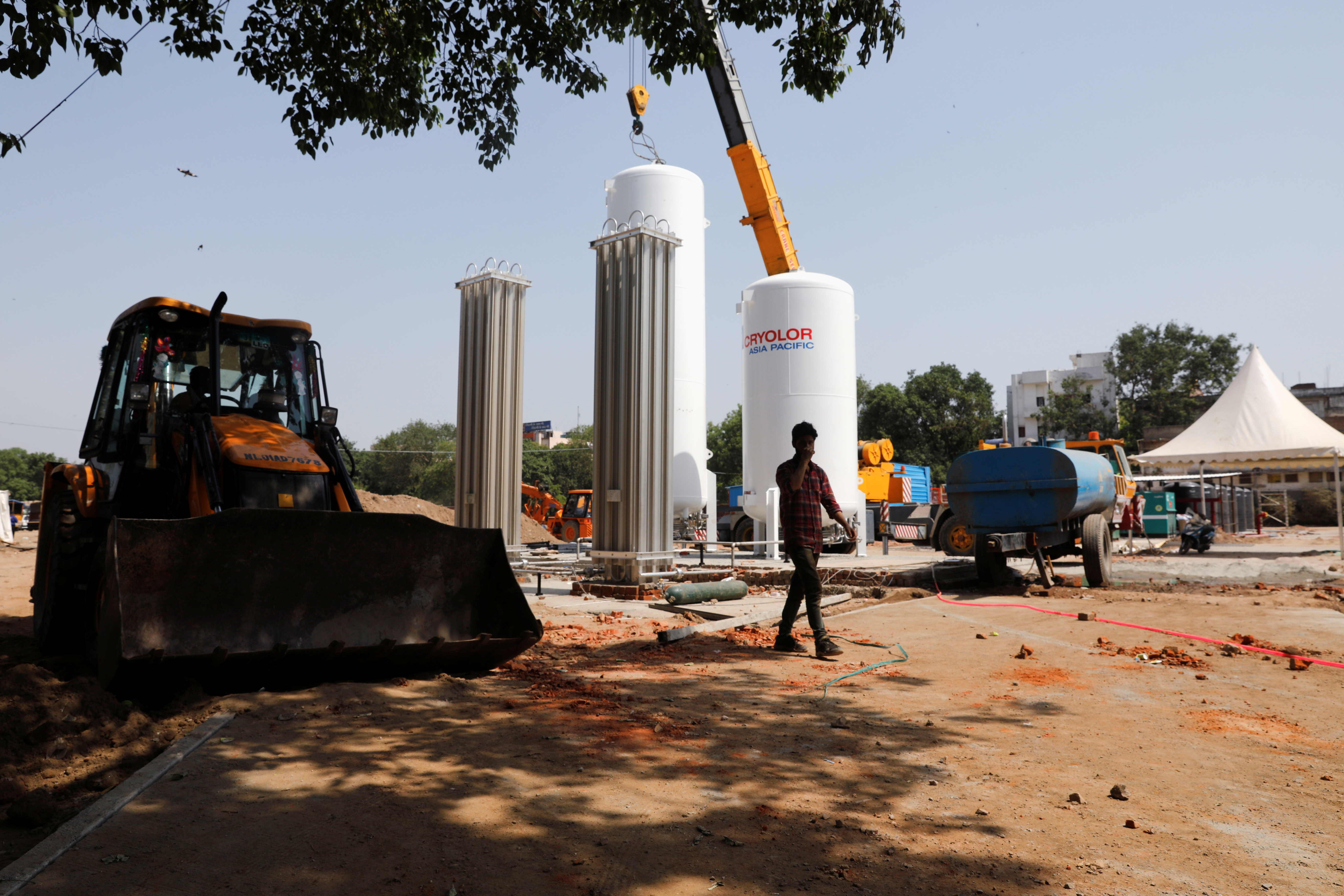 Man walks in front of oxygen tanks at temporary COVID-19 care facility in New Delhi