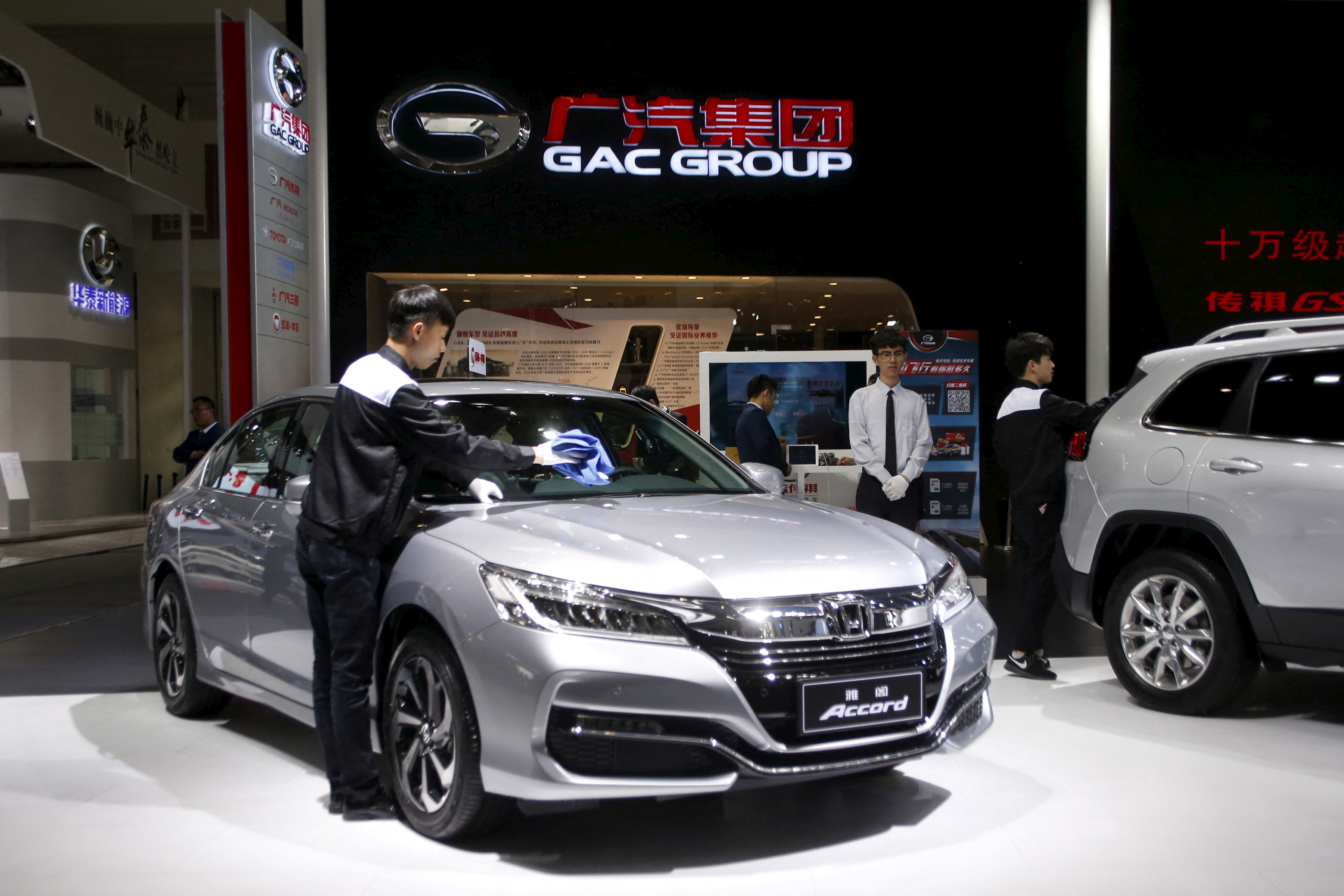 A staff member cleans Honda brand's accord sedan model at the booth of Guangzhou Automobile Group during the Auto China 2016 auto show in Beijing