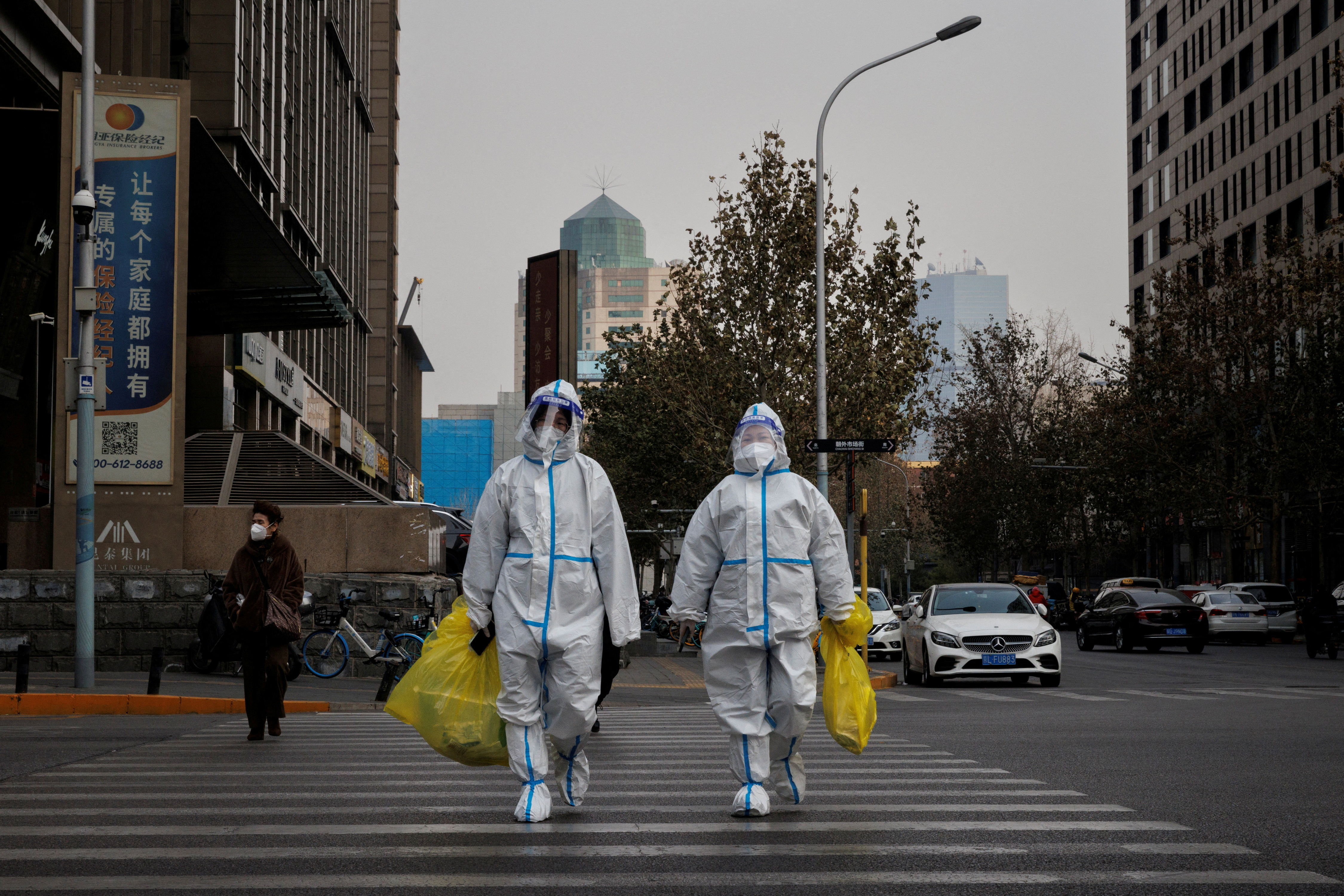 Pandemic prevention workers in protective suits cross a street as coronavirus disease (COVID-19) outbreaks continue in Beijing