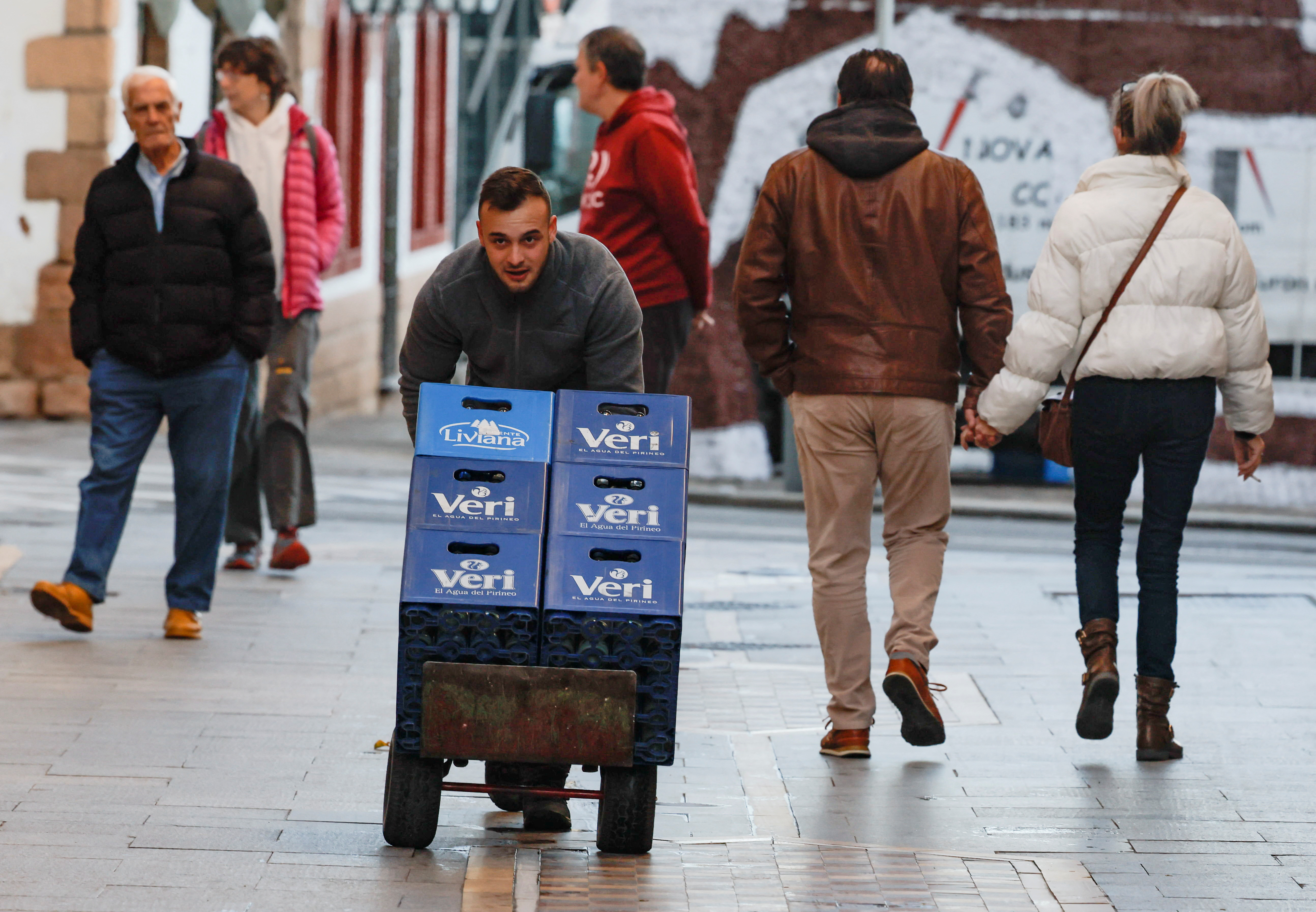 A delivery worker pushes a cart with boxes of water in Ronda
