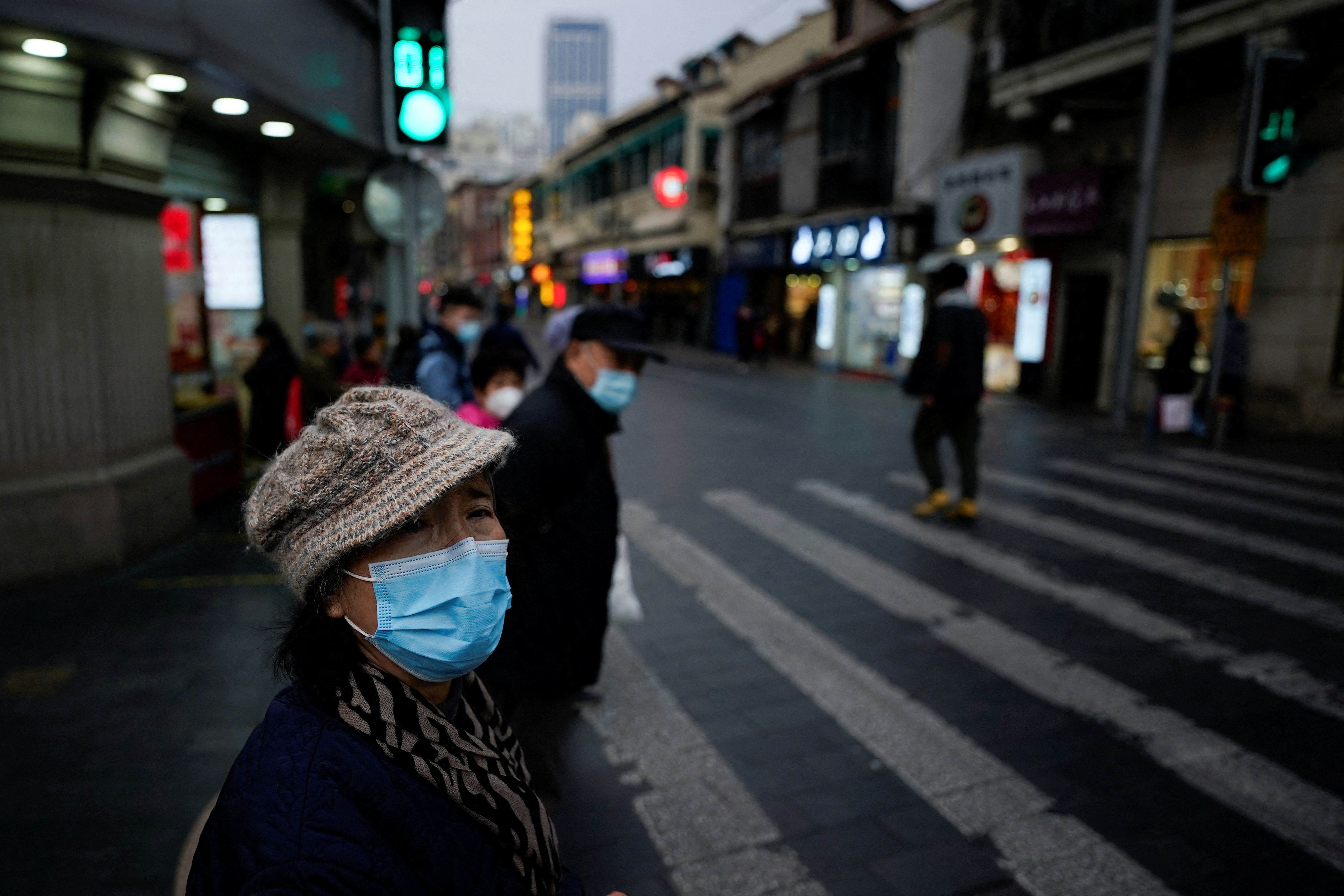 People wearing protective masks walk on a street, following new cases of the coronavirus disease (COVID-19), in Shanghai, China January 4, 2022. REUTERS/Aly Song