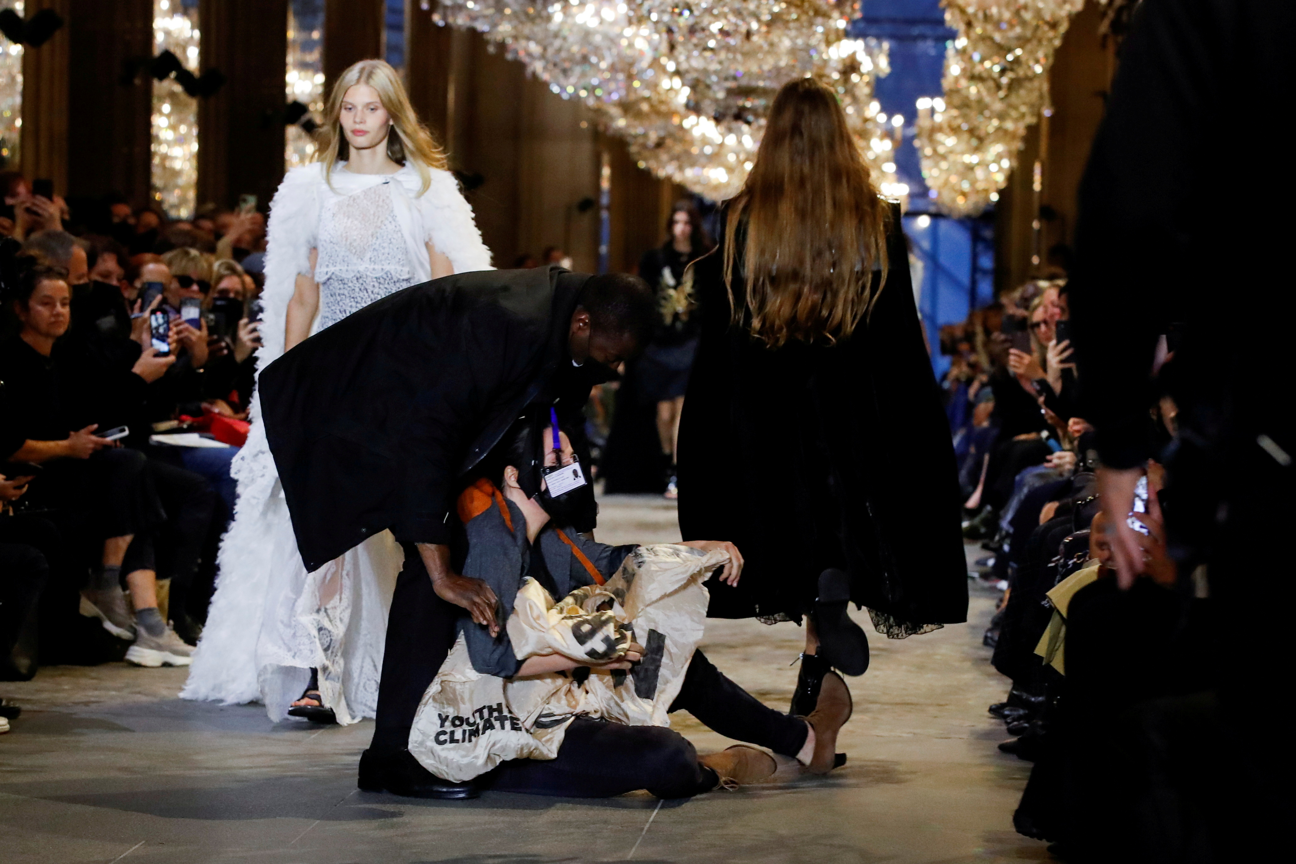 A member of the security personnel removes an activist belonging to the 'Les Amis de la Terre France' or 'Friends of the Earth - France' , who crashed the designer Nicolas Ghesquiere Spring/Summer 2022 women's ready-to-wear collection show for fashion house Louis Vuitton during Paris Fashion Week in Paris, France, October 5, 2021. REUTERS/Gonzalo Fuentes