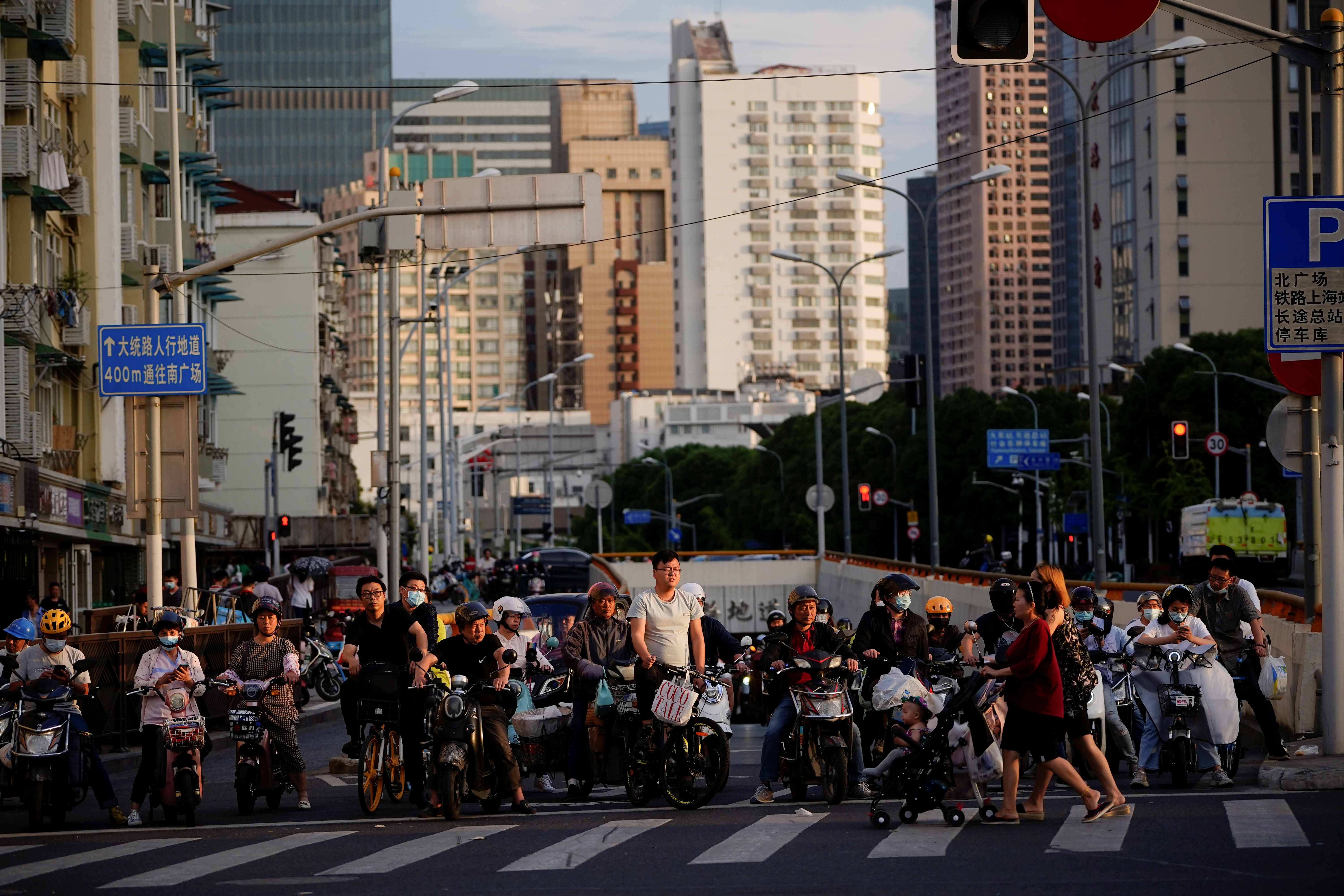 People riding bicycles and motorbikes wait in traffic, amid the coronavirus disease pandemic, in Shanghai