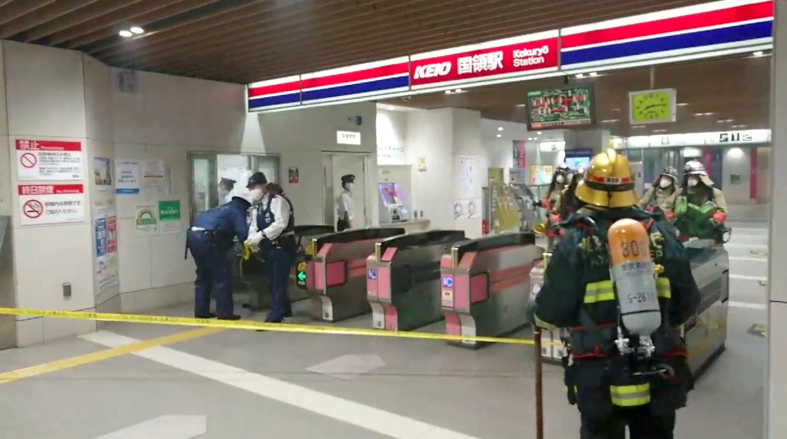 Firefighters and officers work at a Tokyo train station following a knife, arson and acid attack