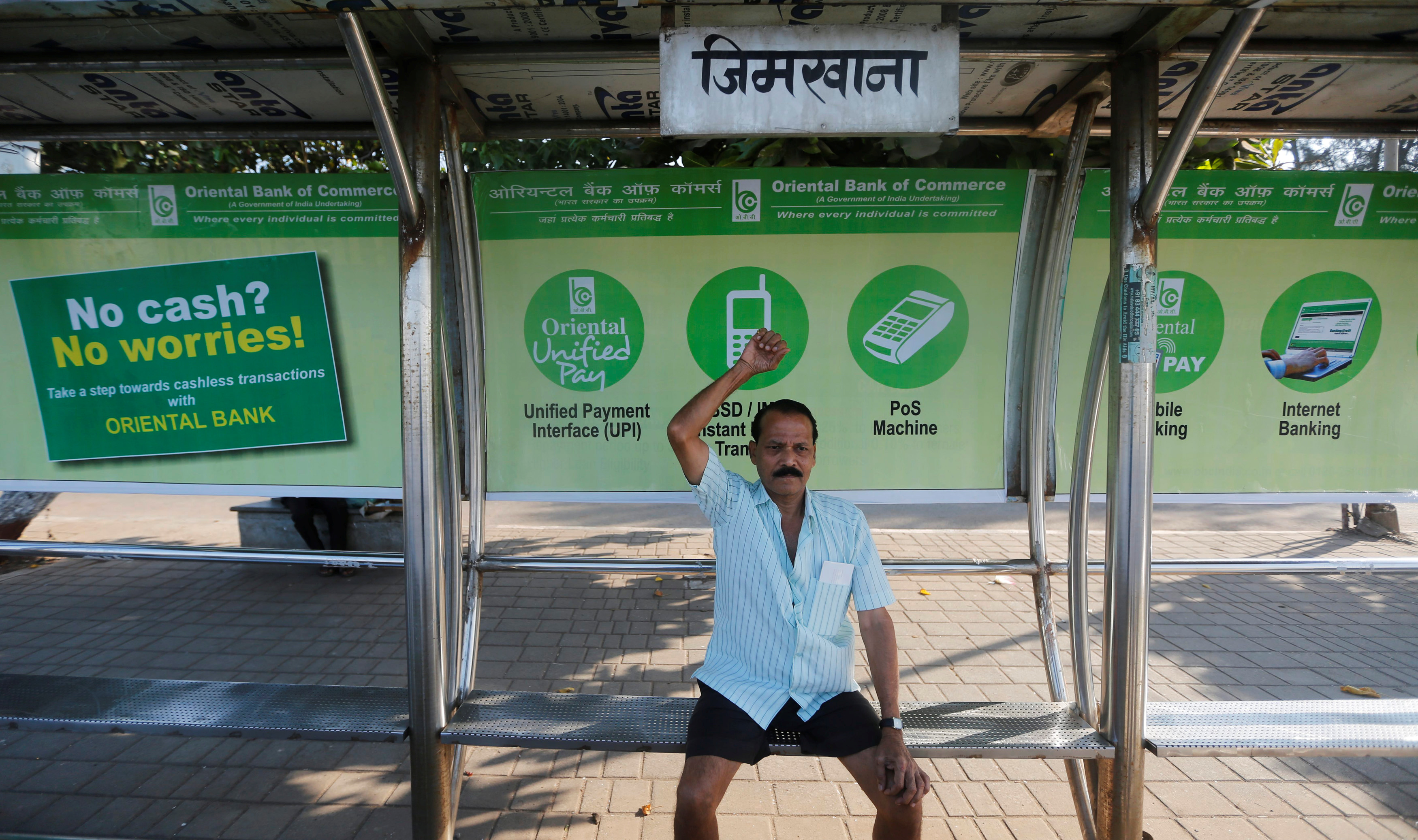 A man exercises on a bus stop with hoardings promoting digital payments in Mumbai