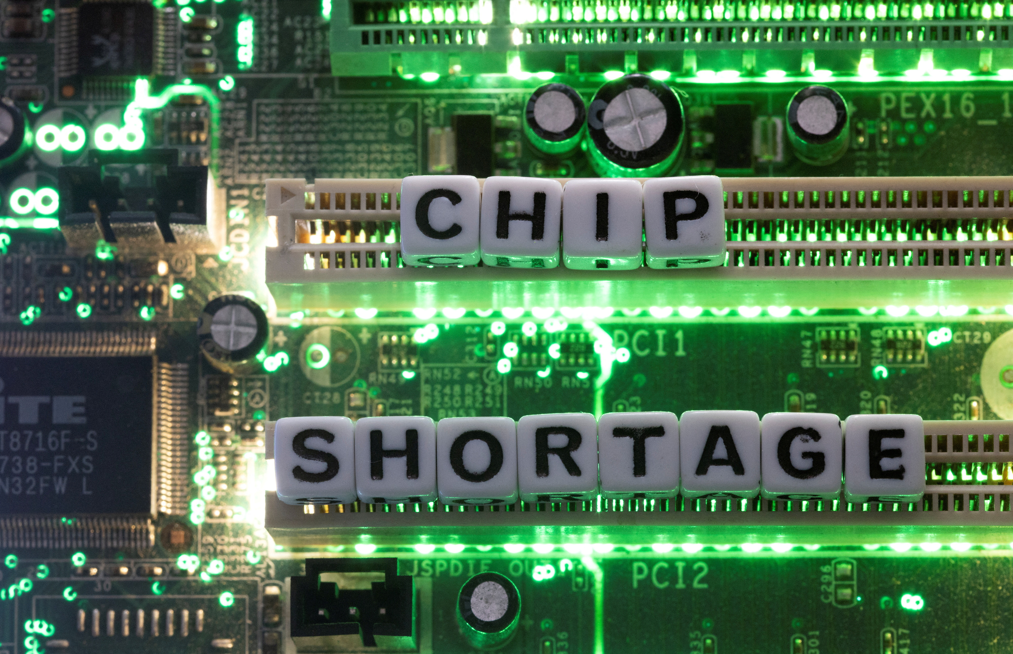 Illustration shows plastic letters arranged to read "Chip Shortage" placed on a computer motherboard