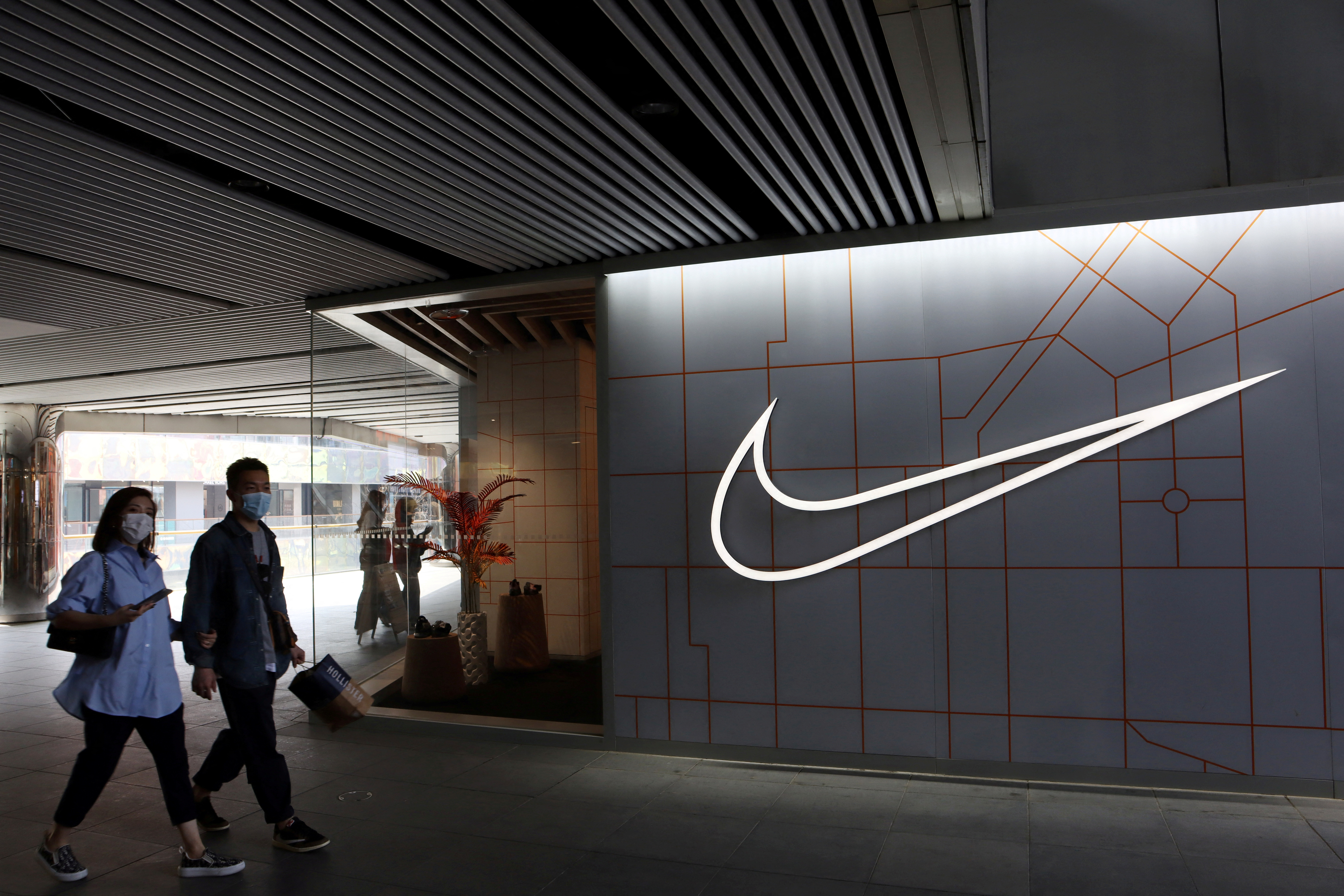 People walk past a Nike Inc store at a shopping complex in Beijing