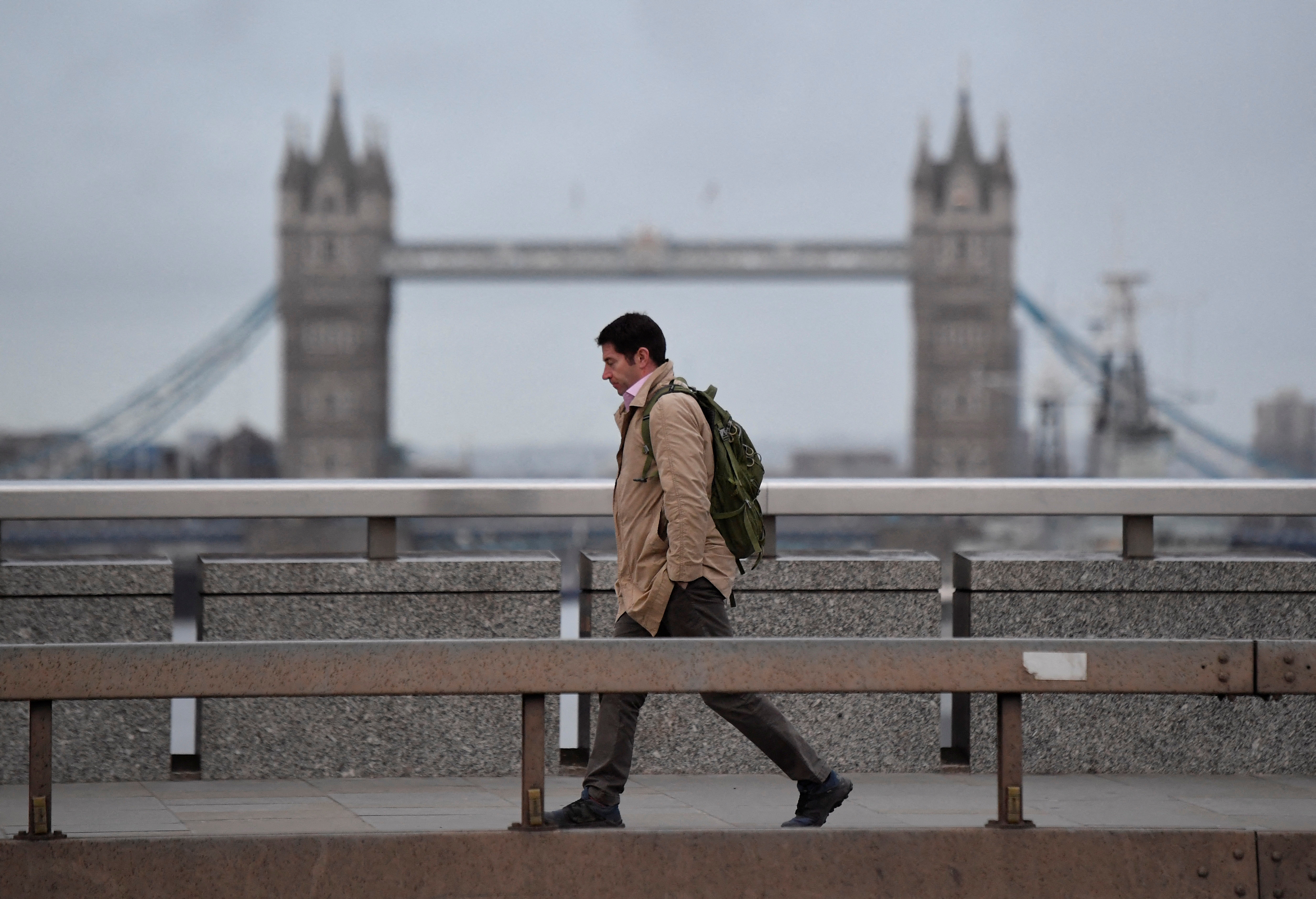 A worker crosses London Bridge during the morning rush-hour, in London